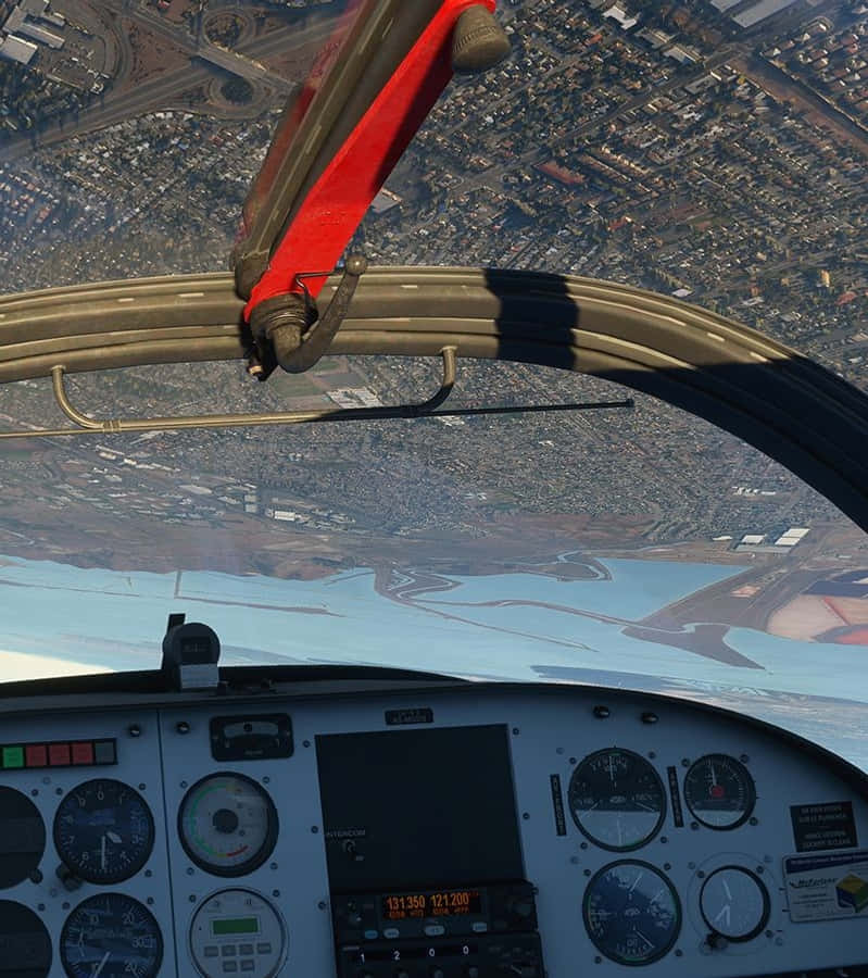 Android Microsoft Flight Simulator 桌布 壁紙 — 從小型飛機駕駛艙拍攝的鳥瞰圖，顯示儀表板和下方廣闊的城市景觀。