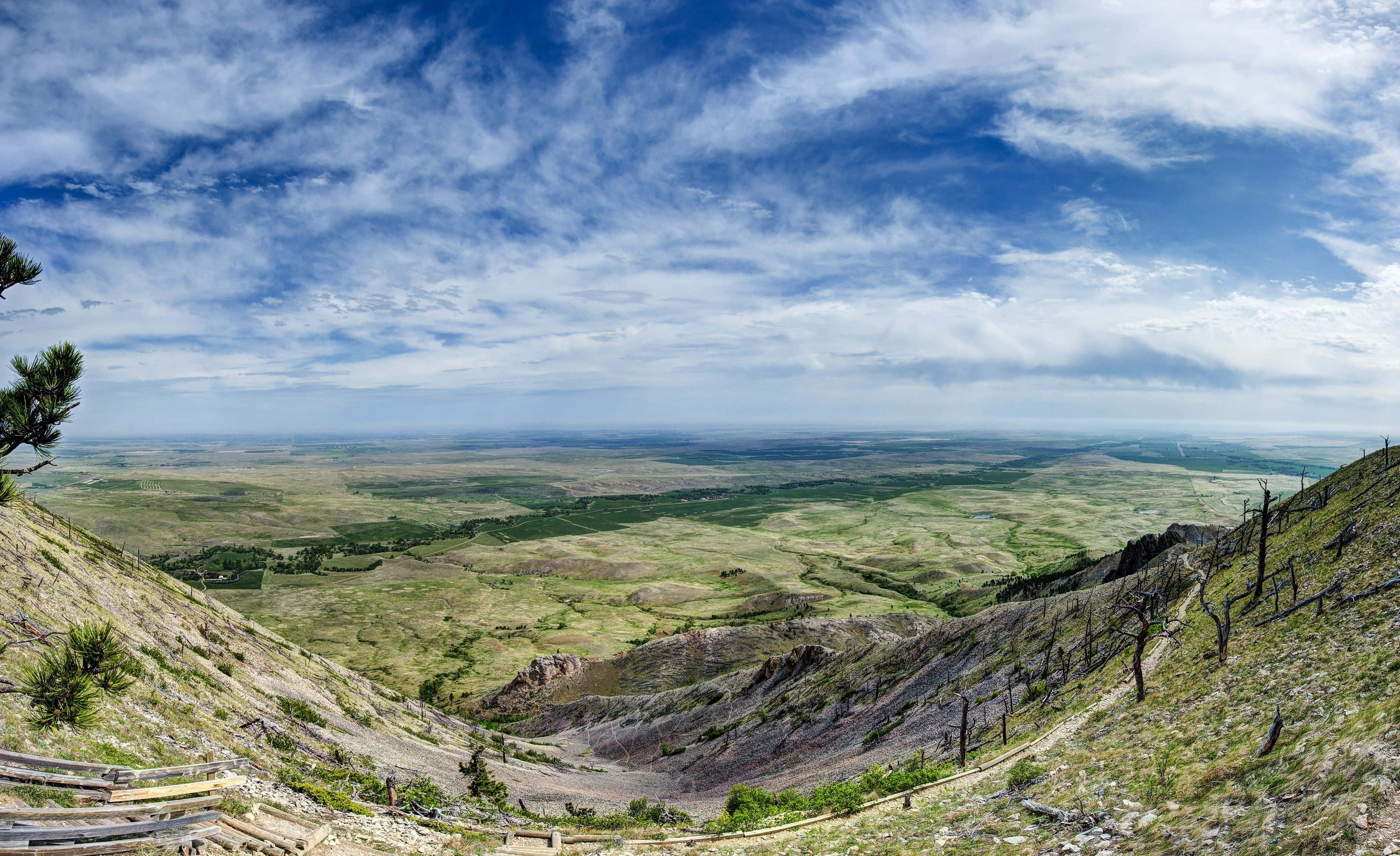 North Dakota 桌布 壁紙 — 從山脊俯瞰廣闊綠色山谷的全景，天空湛藍，雲朵點綴。