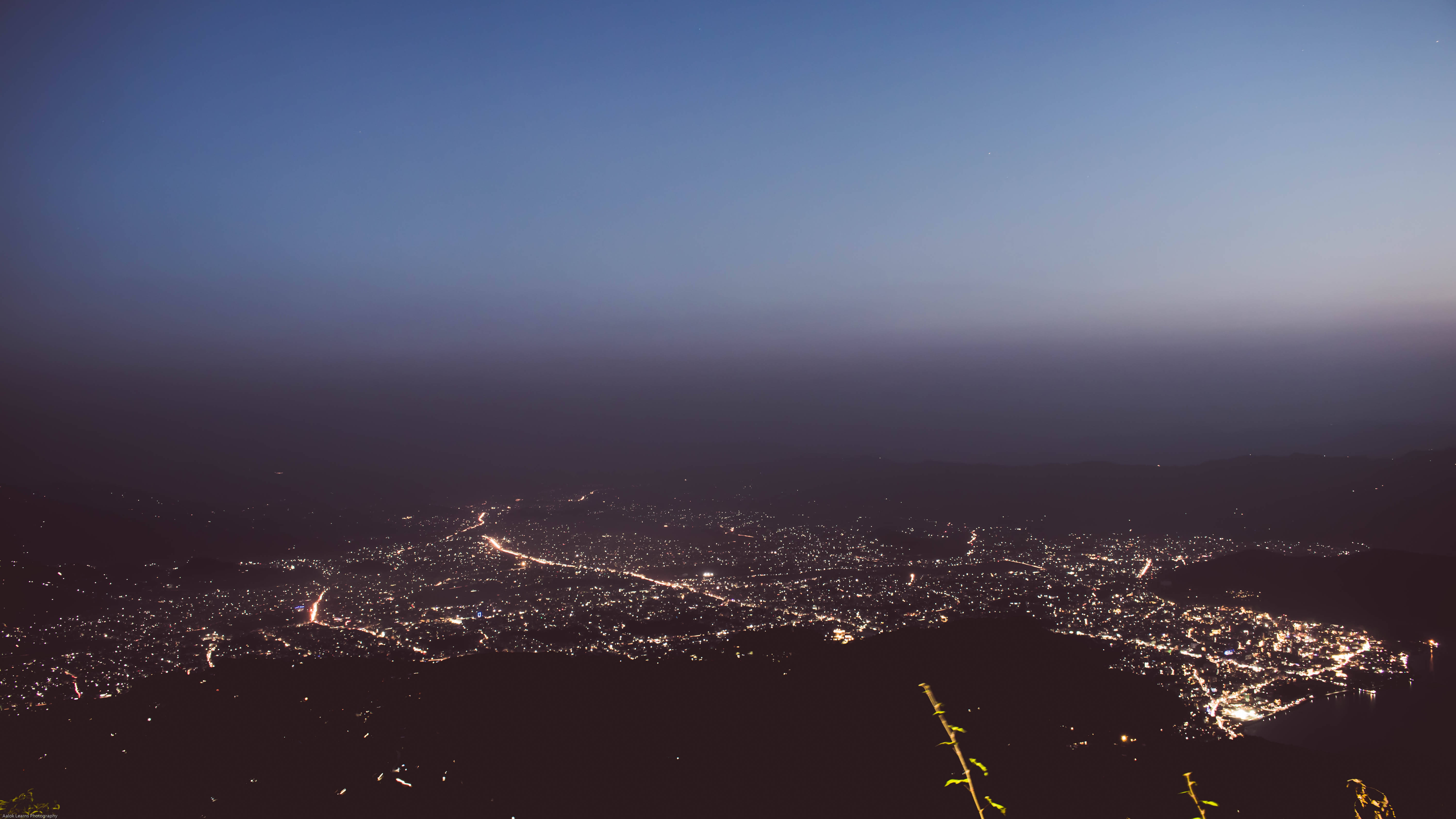 Nepal 桌布 壁紙 — 從山頂俯瞰，一座廣闊的城市在深邃的暮色天空下閃爍著燈光。