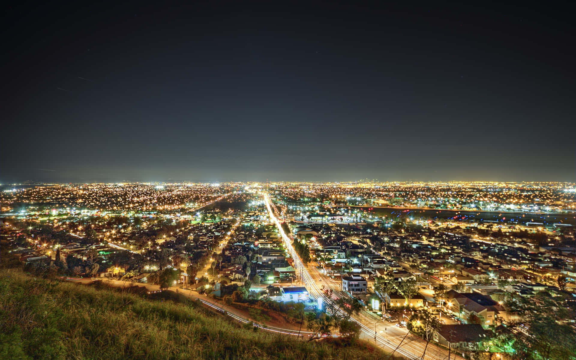 La 桌布 壁紙 — 從山頂俯瞰的廣闊夜景，閃爍的街燈和流動的車燈軌跡。