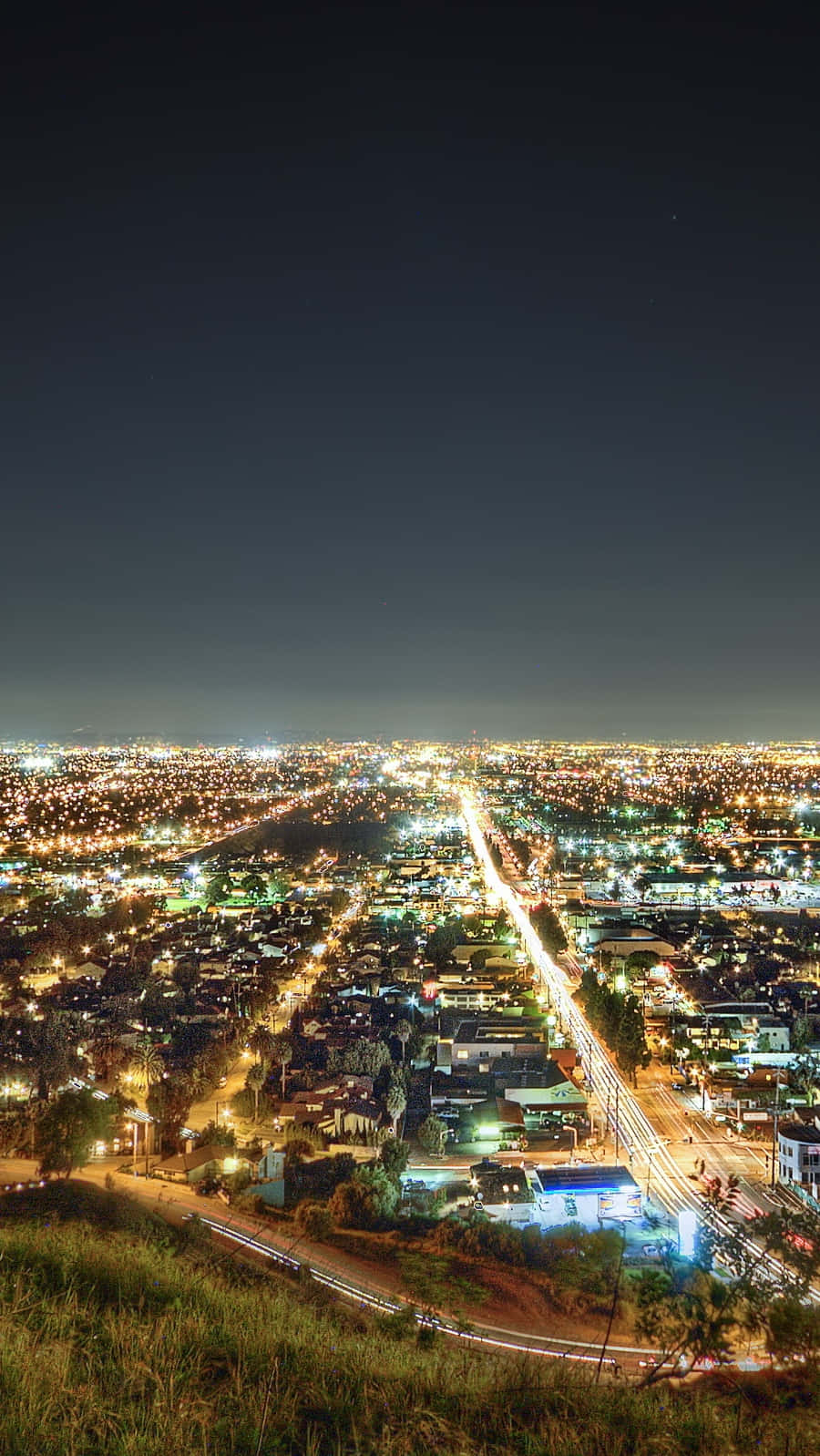 California Aesthetic 桌布 壁紙 — 從山頂俯瞰的廣闊夜景城市景觀，帶有發光的街燈和流動的車流痕跡。