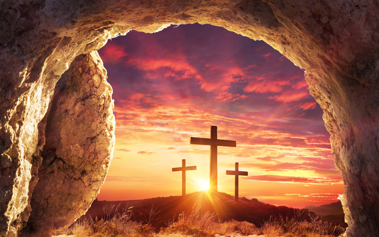 Resurrection 桌布 壁紙 — 從岩石墓穴入口看到的，三個十字架在熾熱日落映襯下的剪影。