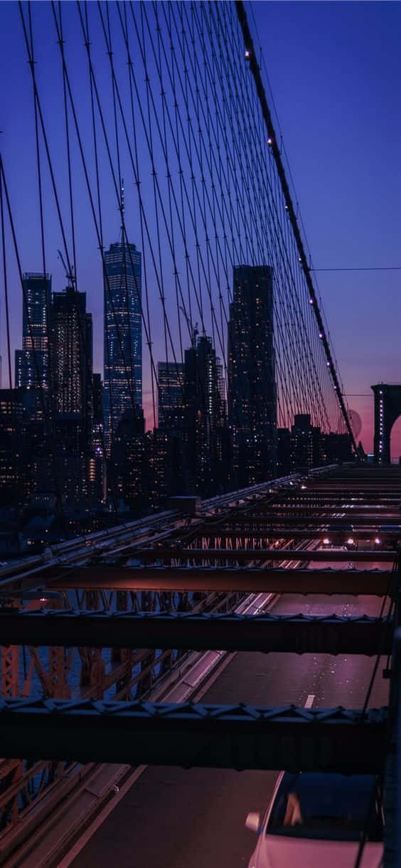 Buildings 桌布 壁紙 — 從布魯克林大橋欣賞的暮色景色，顯示在深紫色天空下閃爍的城市摩天大樓和下方的交通。