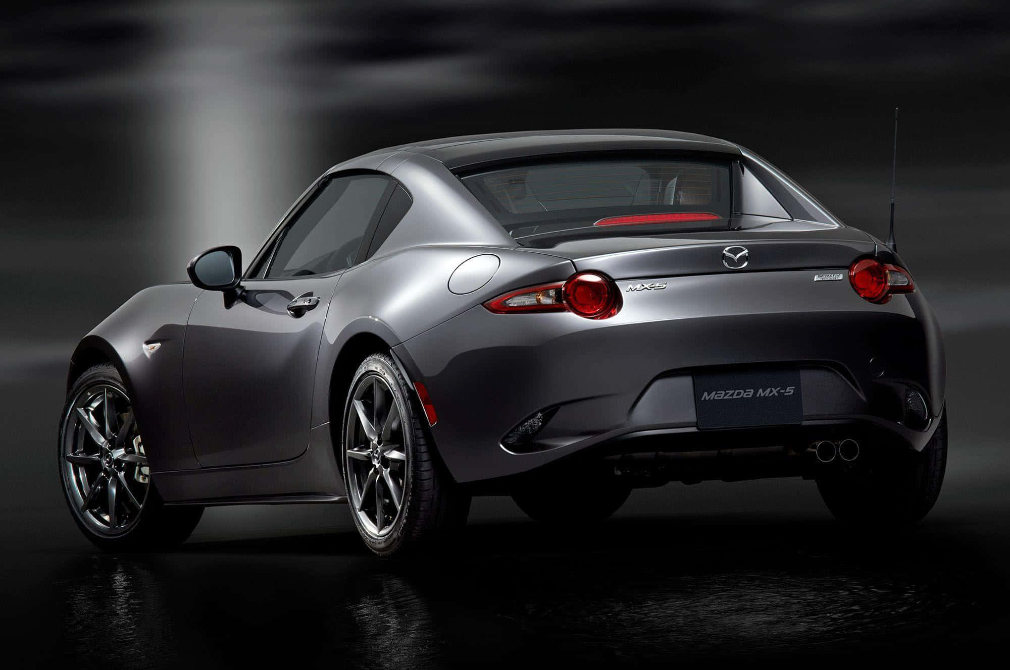 Miata 桌布 壁紙 — 從後方展示一輛時尚的銀色馬自達MX-5 Miata跑車，紅色尾燈在黑暗的攝影棚背景下發光。