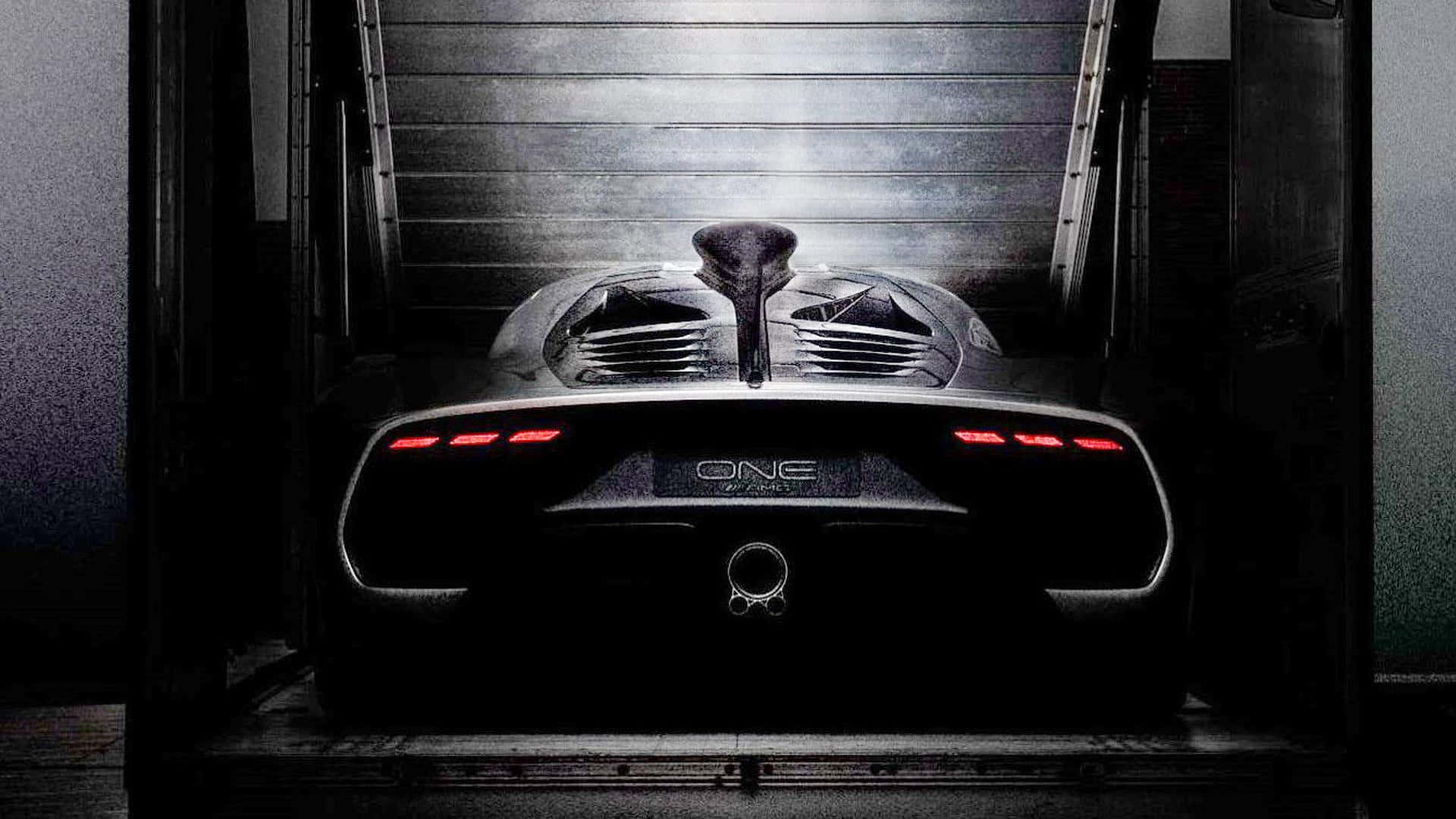 跑車 桌布 壁紙 — 從後方看到的時尚黑色Koenigsegg One-1超級跑車，帶有發光的紅色尾燈，停在光線昏暗的工業車庫中。