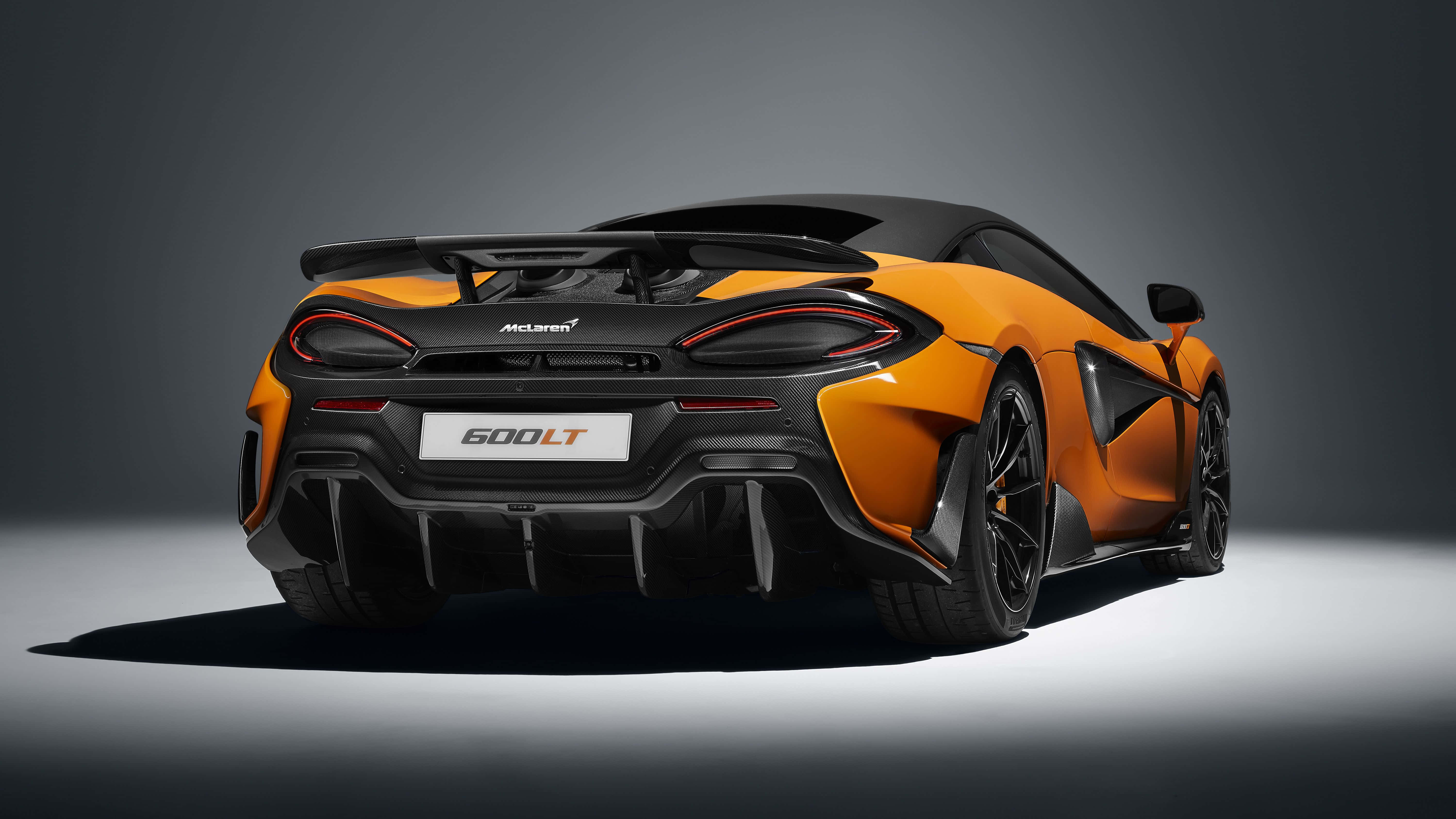 Mclaren 600lt 桌布 壁紙 — 從後方觀看一輛搶眼的橙色McLaren 600LT跑車，背景為簡約灰色工作室。