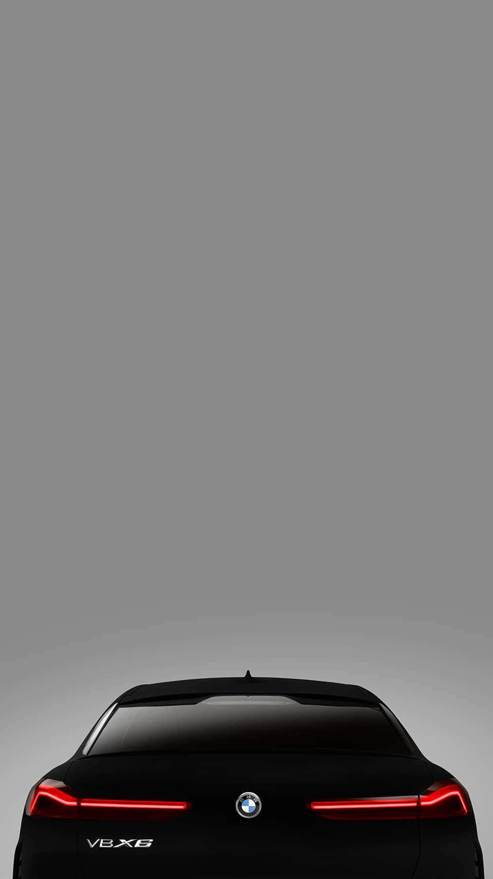 Vantablack 桌布 壁紙 — 從後方觀看一輛時尚的黑色BMW V8X6轎車，紅色尾燈在極簡灰色漸變背景上發光。