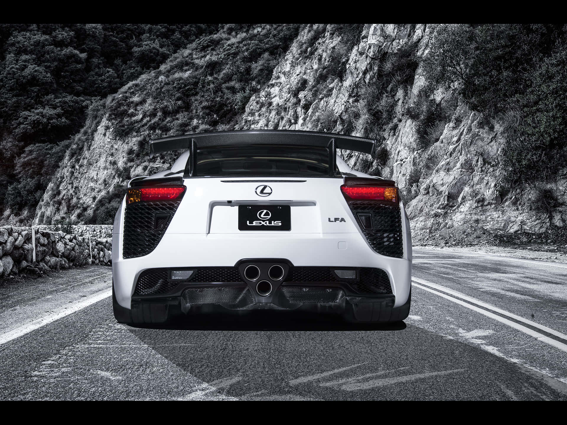 Lexus Lfa 桌布 壁紙 — 從後方觀看一輛白色Lexus LFA跑車行駛在蜿蜒的山路上，兩旁是戲劇性的黑白岩石峭壁。