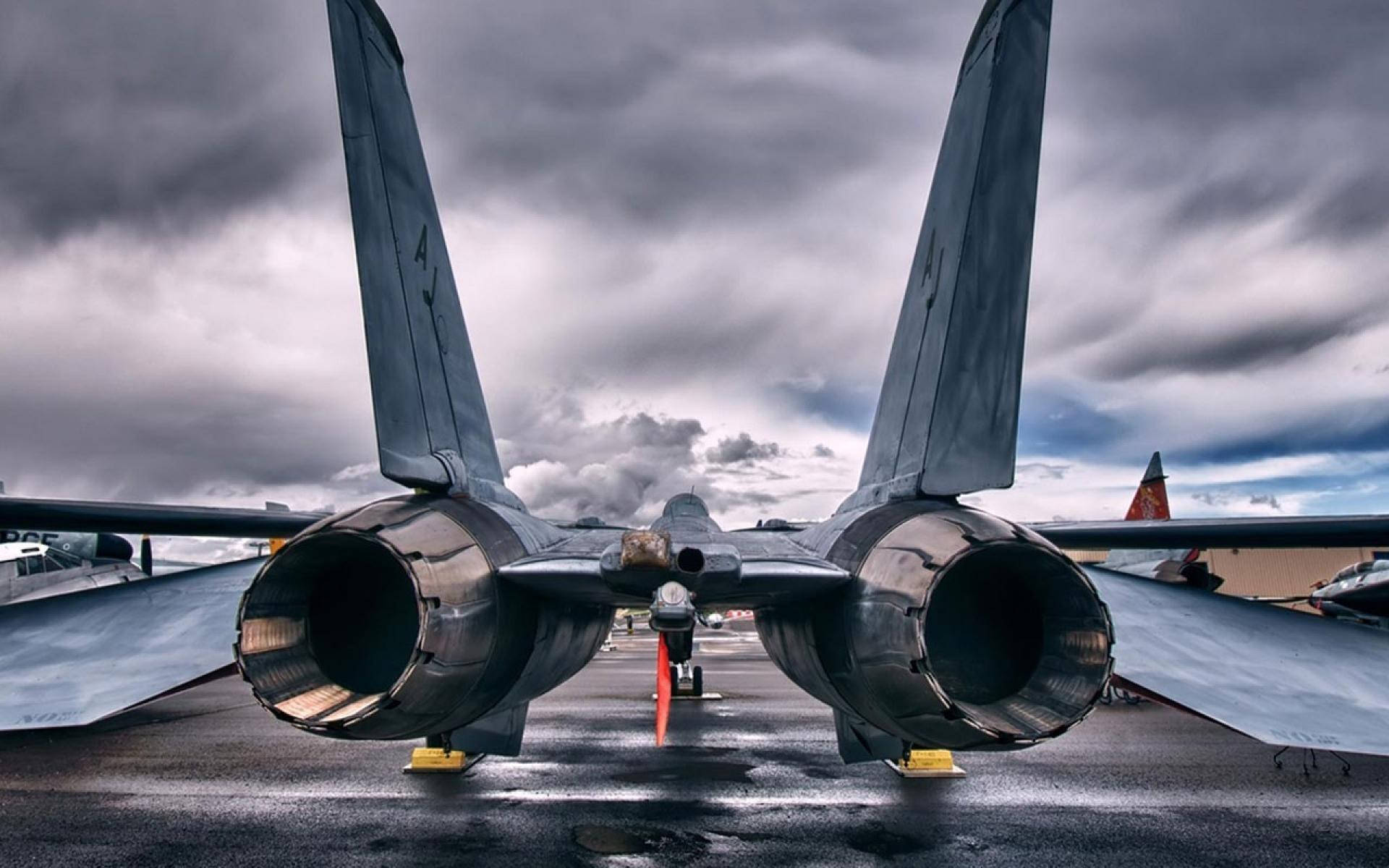 Military Jets 桌布 壁紙 — 從後方觀看的戰鬥機，在潮濕的停機坪上，天空多雲而戲劇化。