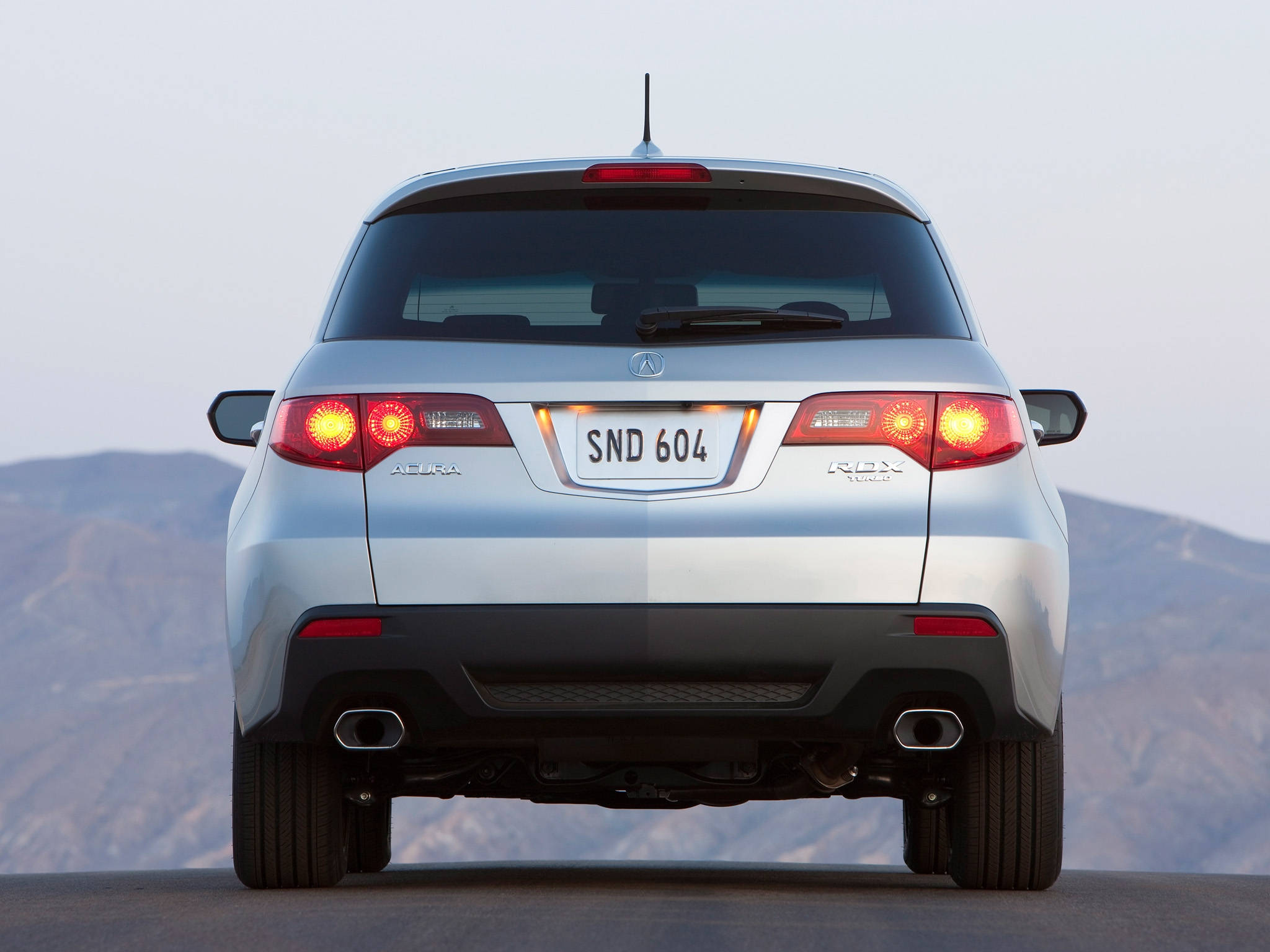 Acura 桌布 壁紙 — 從後方觀看銀色Acura RDX SUV，發光的尾燈，停泊在黃昏的山路上。