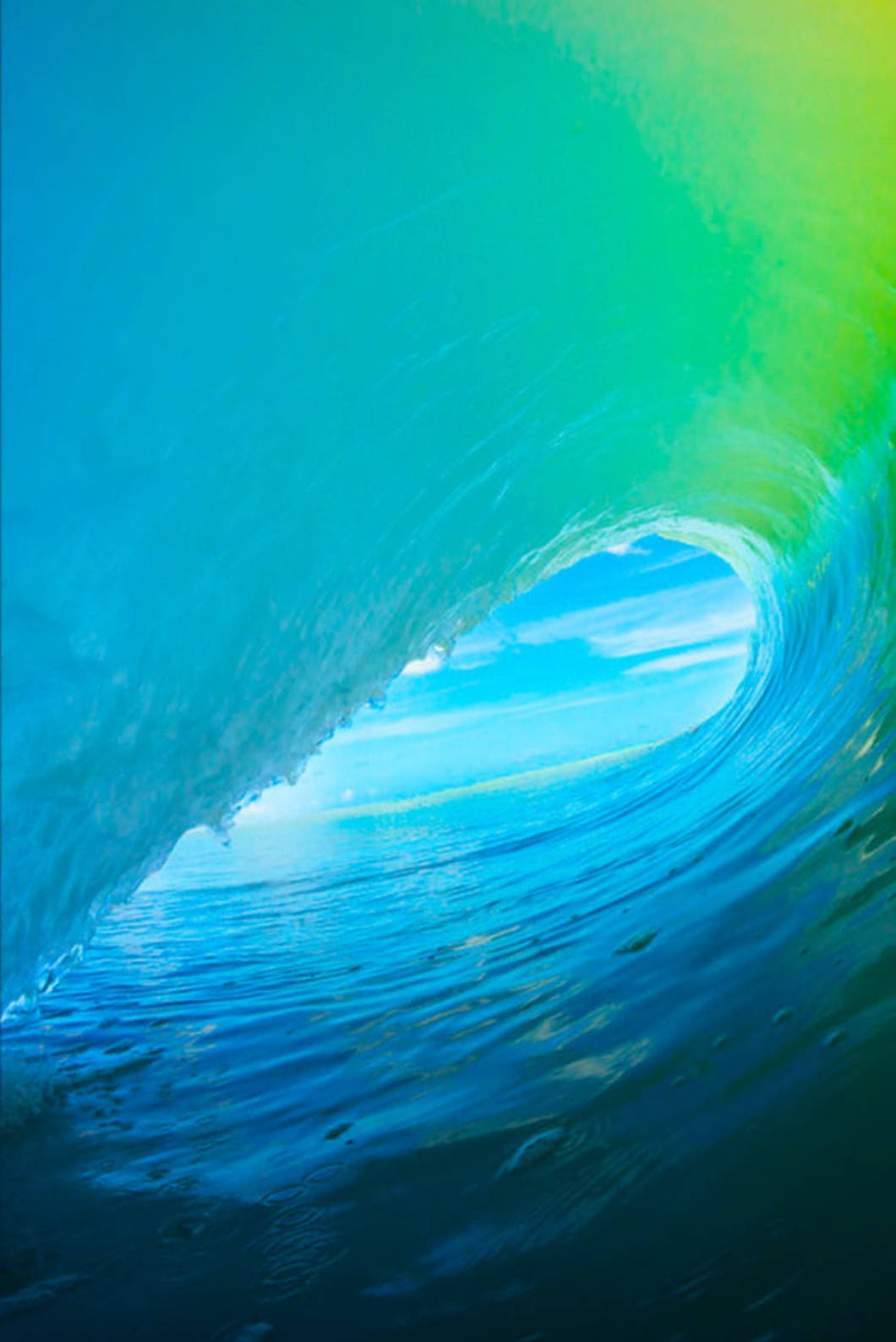 iPhone 桌布 壁紙 — 從捲曲的海浪內部欣賞壯麗景色，充滿活力的藍色和綠色色調，露出遠處明亮的天空。