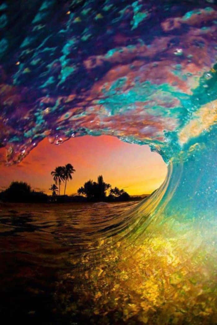 海洋 桌布 壁紙 — 從捲曲的海浪內部看到的充滿活力的水下景色，揭示了岸邊有棕櫚樹的熱帶日落。