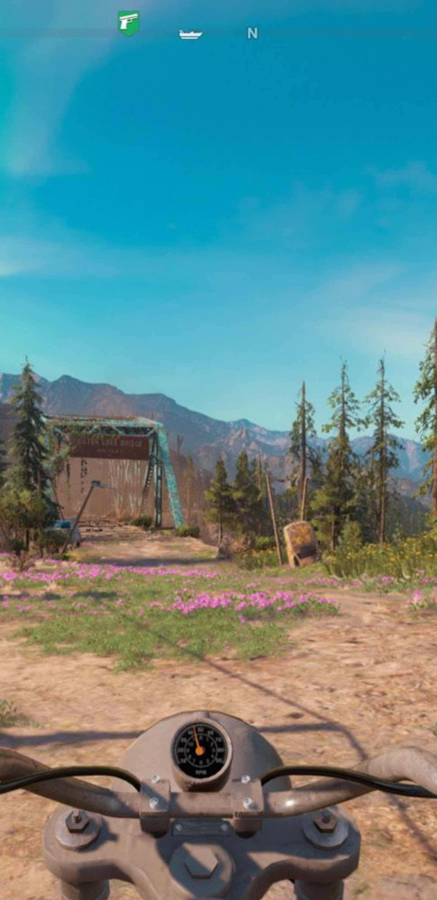 Android Far Cry New Dawn 桌布 壁紙 — 從摩托車上以第一人稱視角，在晴朗藍天下，駛向一個位於點綴著粉紅色野花的山區荒野中的生鏽大門。