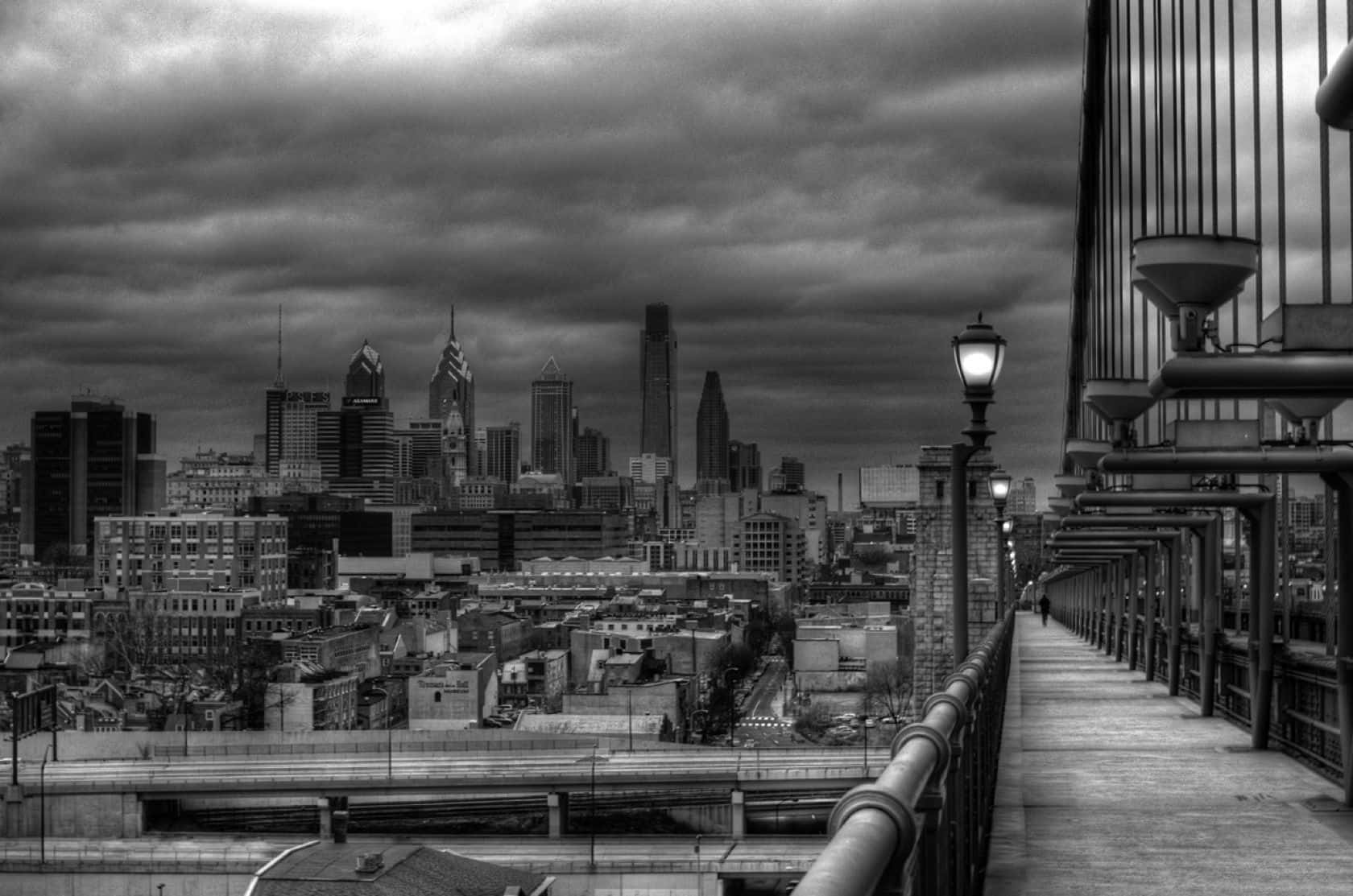 Black And White Cityscape 桌布 壁紙 — 從橋上俯瞰密集城市天際線，在厚重雲層下的陰鬱黑白景觀。