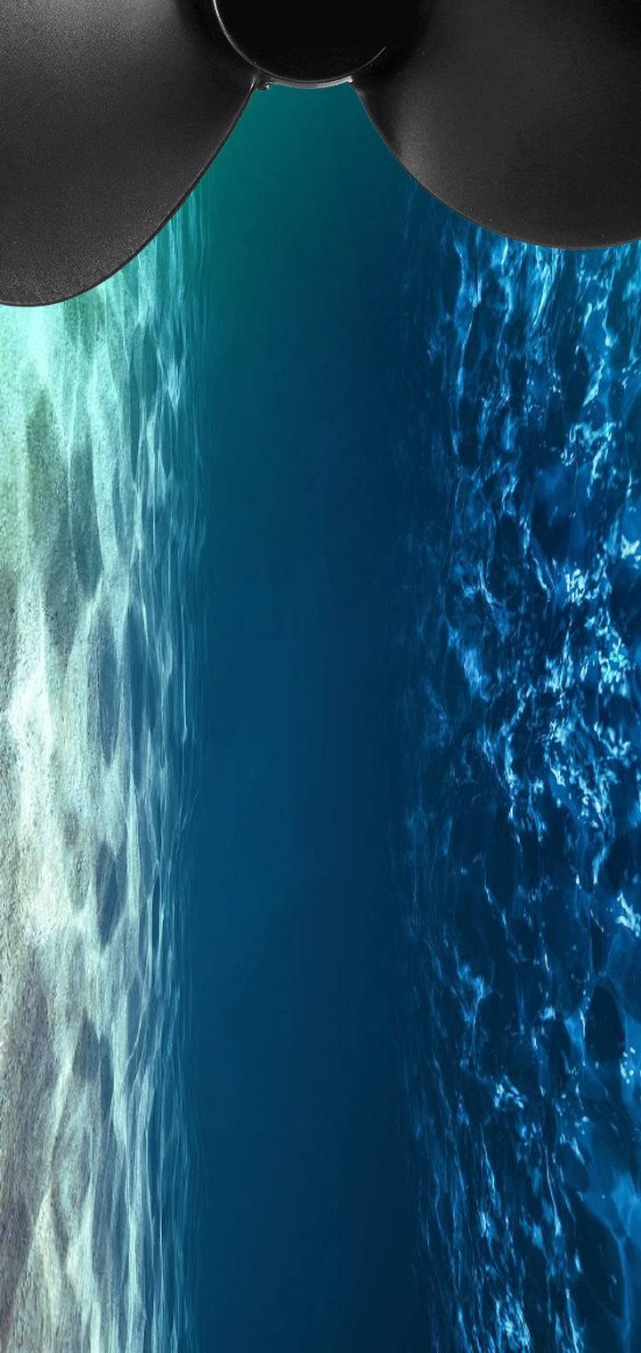 drop 桌布 壁紙 — 從水下透過船螺旋槳向上看，陽光照射的海面與旋轉的藍綠色海水。