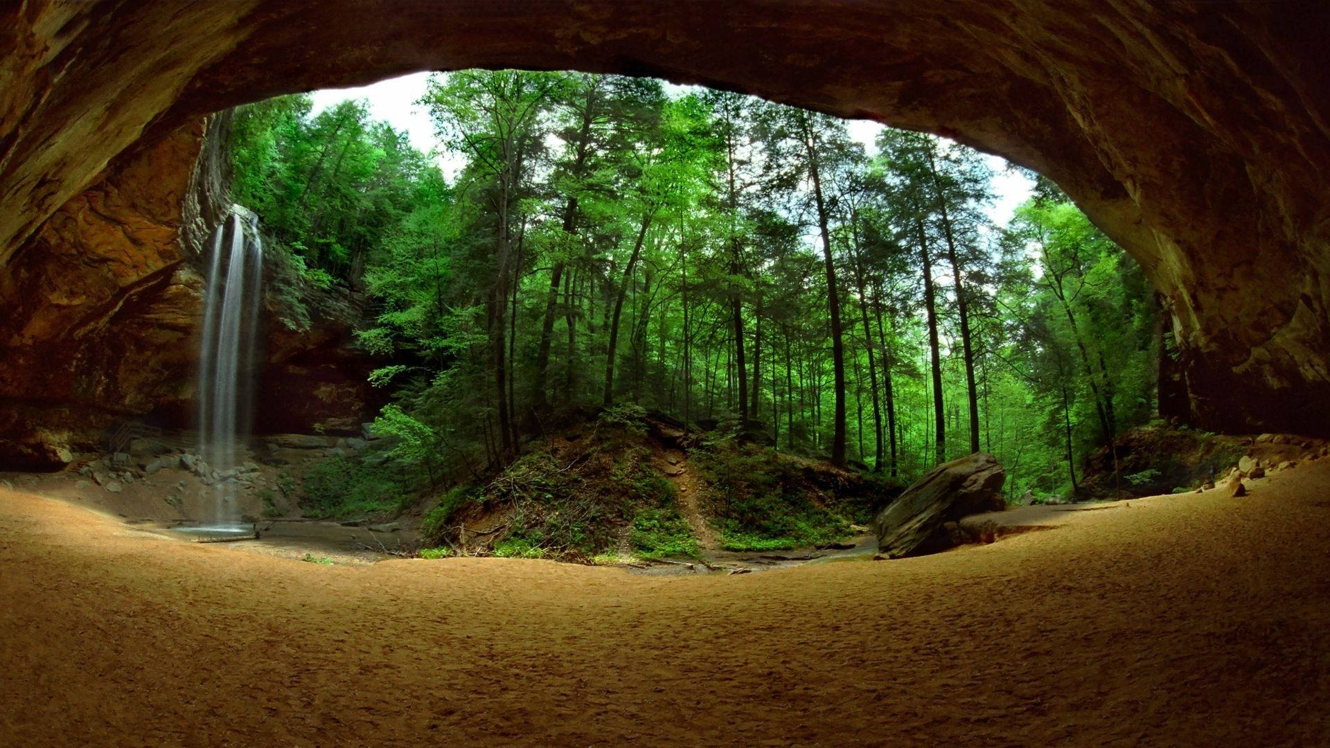 Cave 桌布 壁紙 — 從洞穴內向外望，一片鬱鬱蔥蔥的森林，瀑布從懸崖傾瀉而下，景色壯麗。
