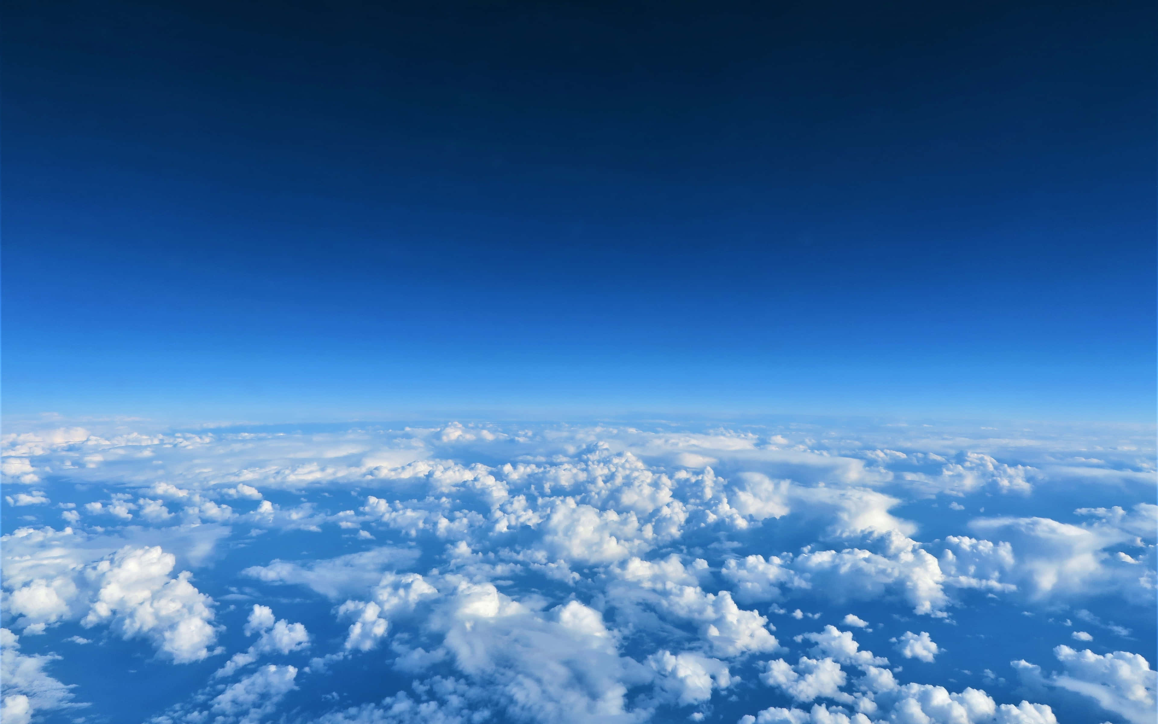 Clouds Aesthetics 桌布 壁紙 — 從深藍到淺藍漸變的天空下，蓬鬆白雲綿延的航拍視角。