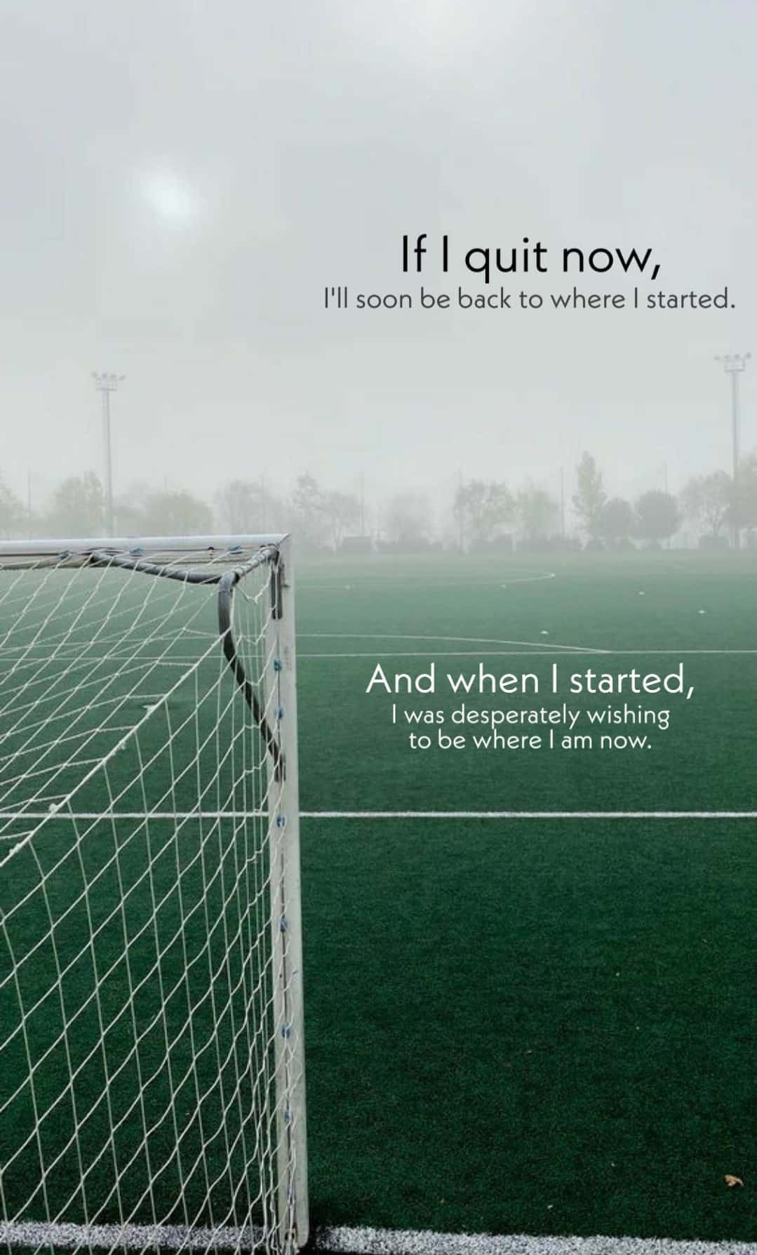 Football Field 桌布 壁紙 — 從球門網看到的霧氣足球場，帶有勵志文字疊加。