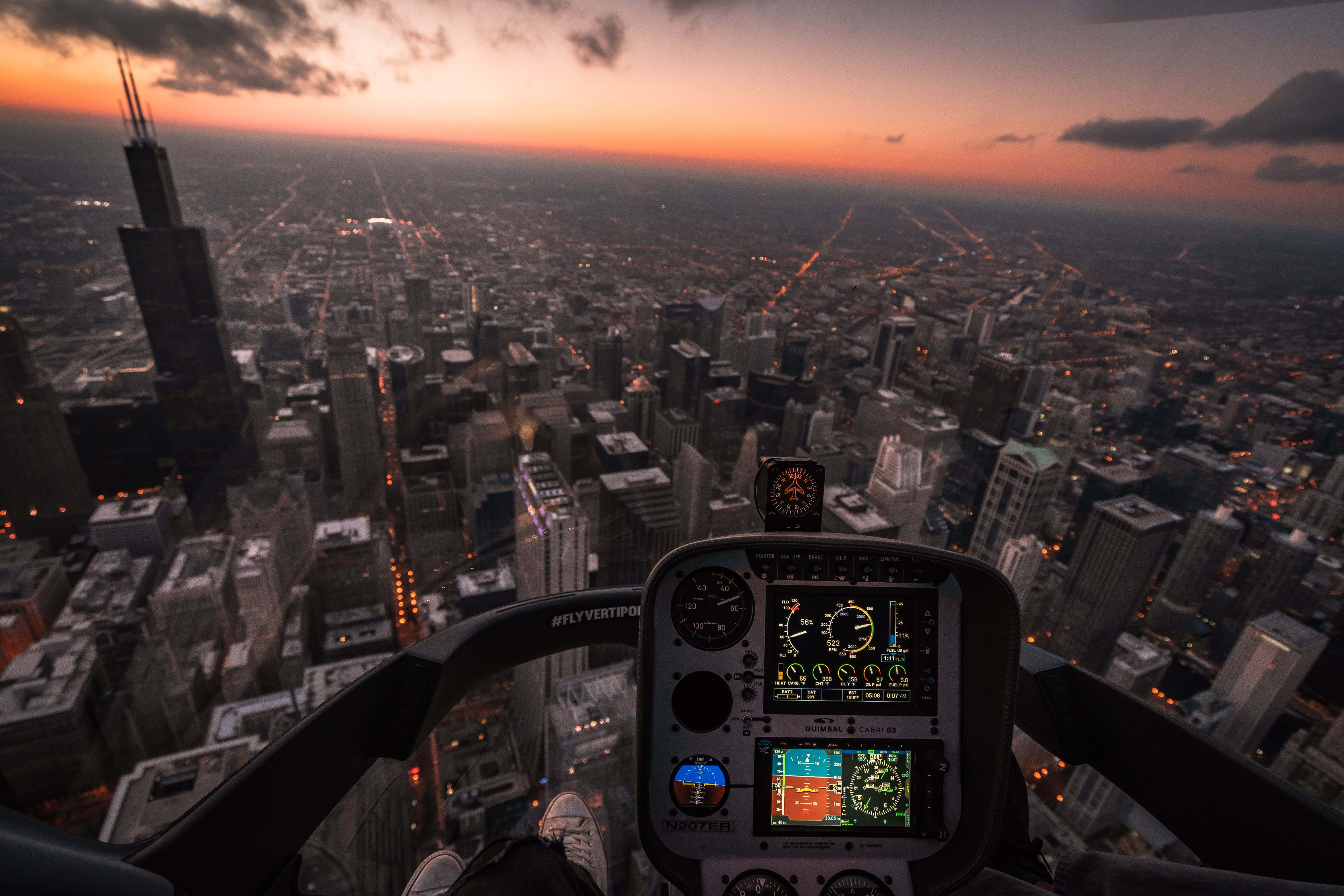 Helicopter 桌布 壁紙 — 從直升機駕駛艙俯瞰芝加哥璀璨天際線和廣闊城市網格的壯麗日落景色。