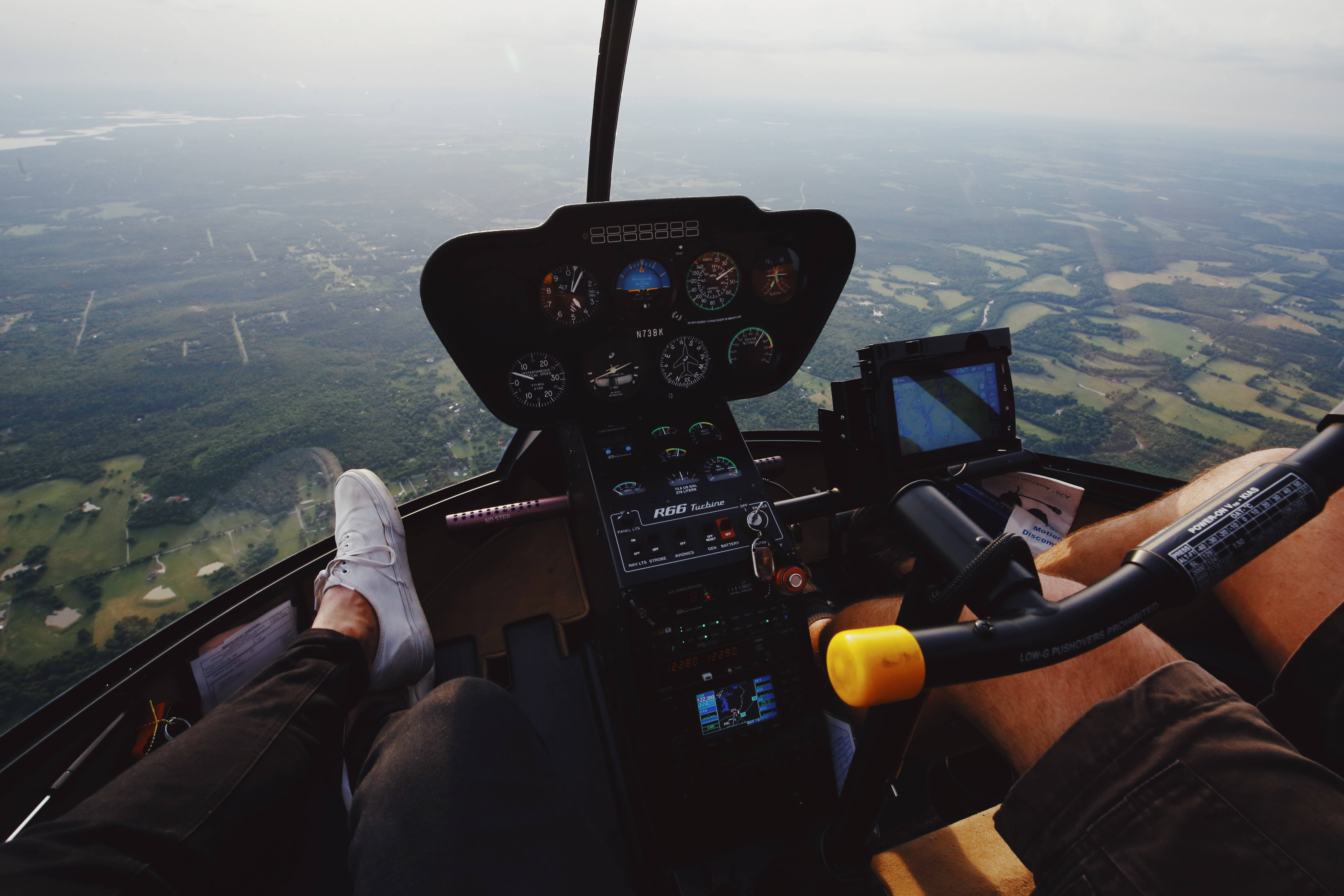 Helicopter 桌布 壁紙 — 從直升機駕駛艙內部以第一人稱視角飛越由綠色田野和道路組成的拼布景觀。