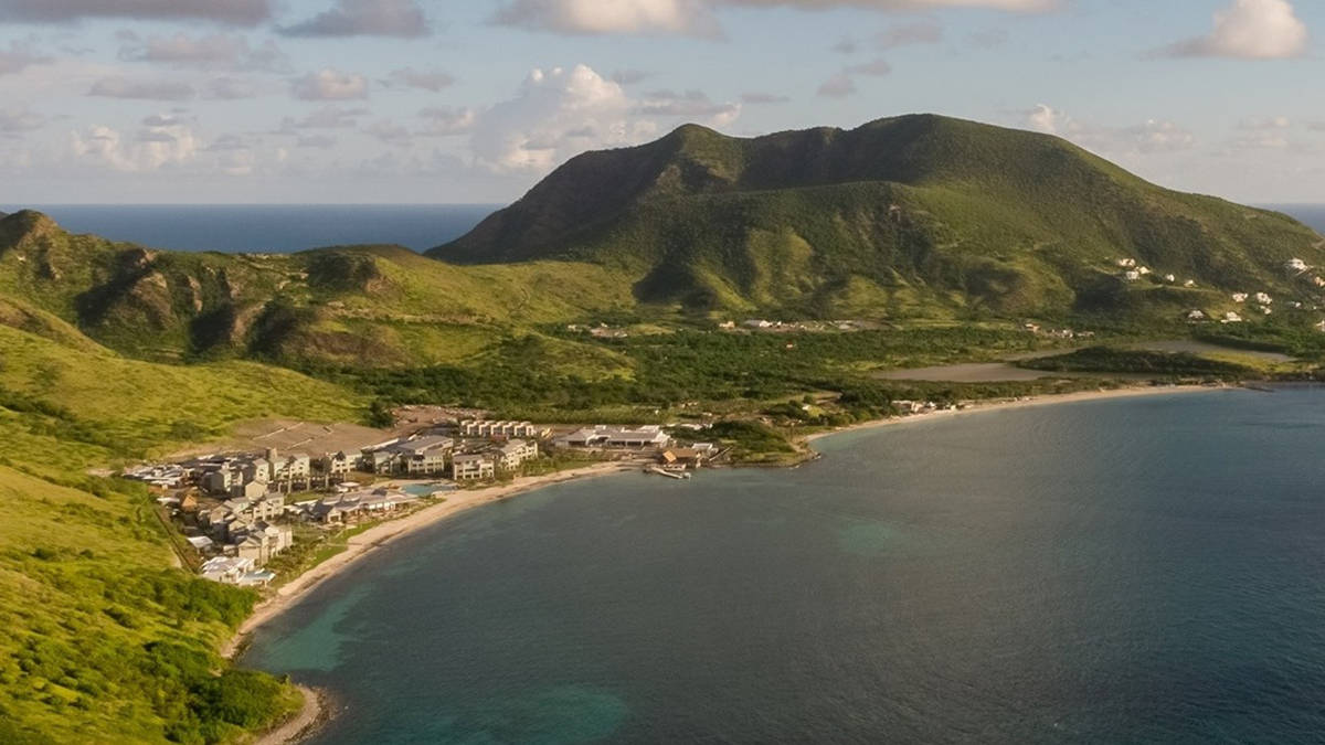 Caribbean 桌布 壁紙 — 從空中俯瞰，一個沿海度假村坐落在鬱鬱蔥蔥的綠色山丘和碧綠海水之間，天空部分多雲。
