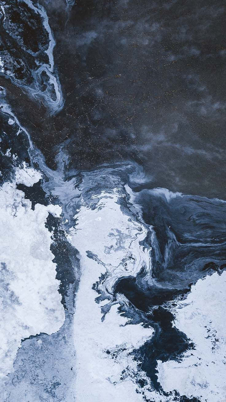 桌布 壁紙 — 從空中俯瞰，深色漩渦洋流與冰冷白色海冰交匯，形成戲劇性的自然圖案。