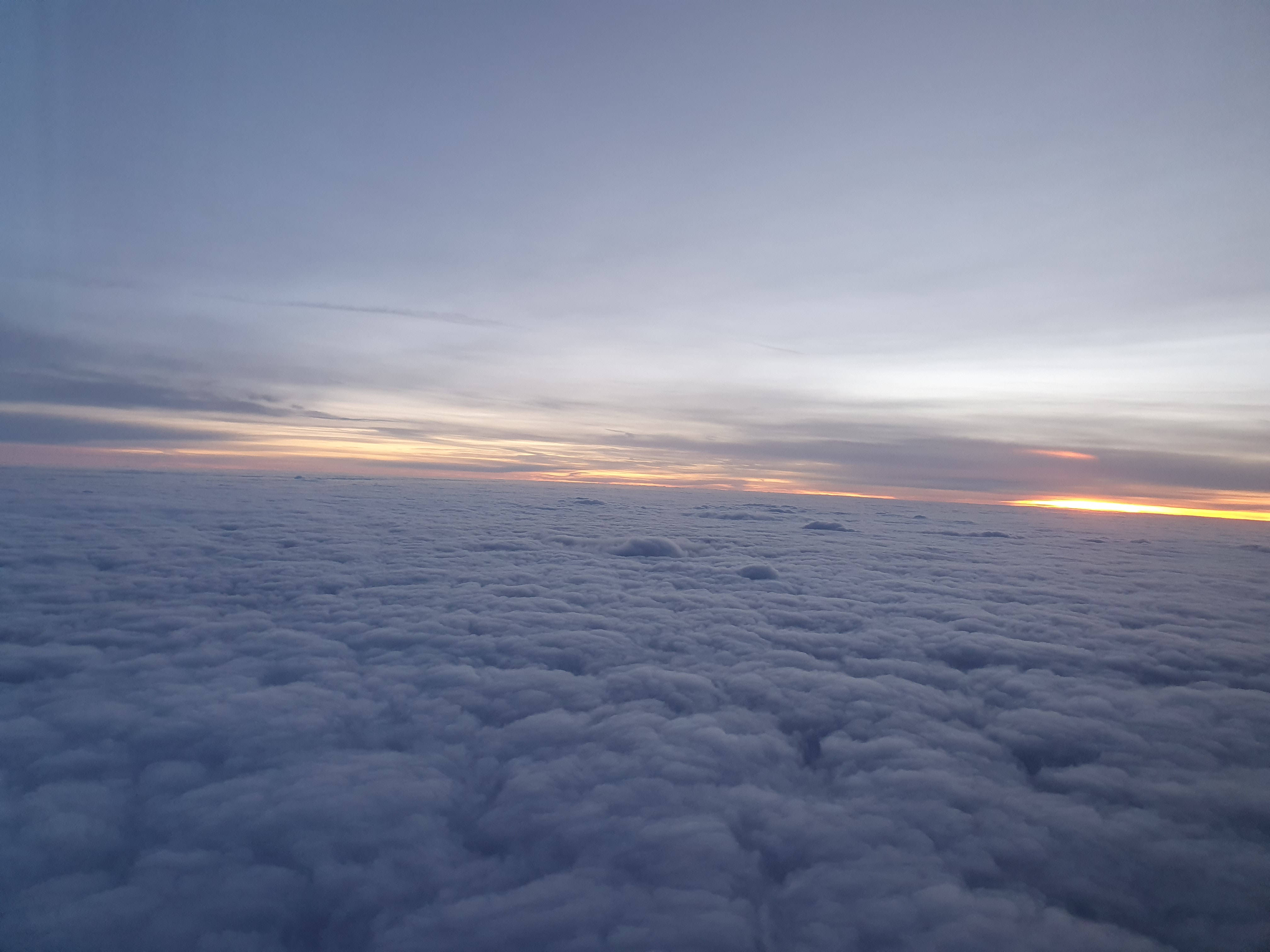 Rwanda 桌布 壁紙 — 從空中俯瞰，無盡的棉花雲沐浴在柔和的金色夕陽色調中，映襯著暮色天空。