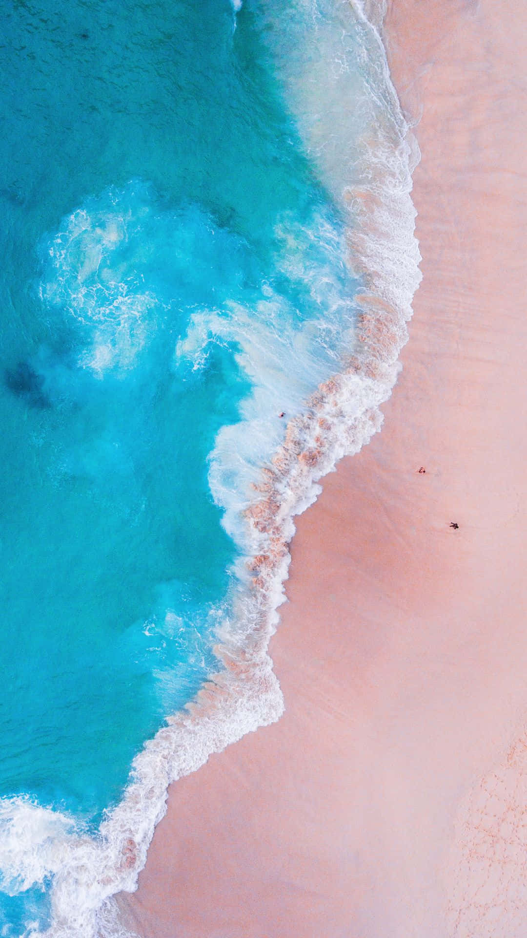 Pink Beach 桌布 壁紙 — 從空中俯瞰，碧綠色的海浪拍打著柔軟的粉紅色沙灘，小小的身影正在享受海濱。