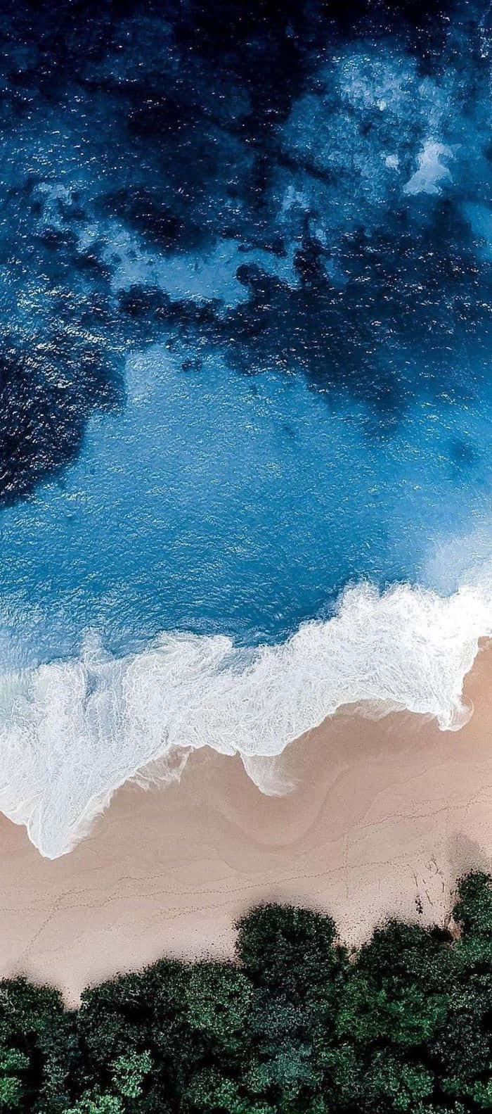 海灘 桌布 壁紙 — 從空中俯瞰，綠松石色的海浪拍打著沙灘，沙灘邊緣被茂密的綠色植物環繞。