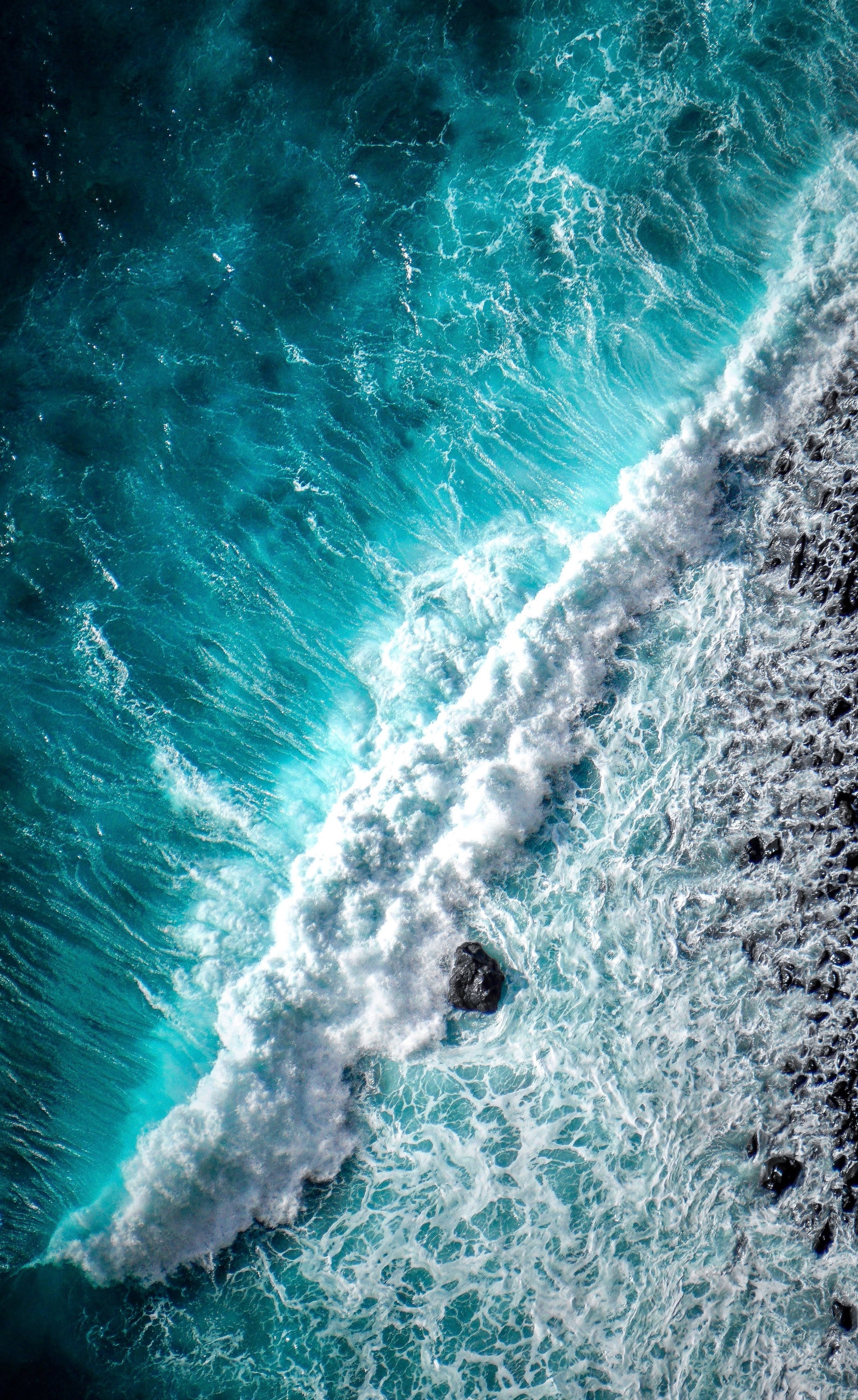 Wave 桌布 壁紙 — 從空中俯瞰，綠松石色的海浪拍打著深色火山岩，形成戲劇性的海岸場景。