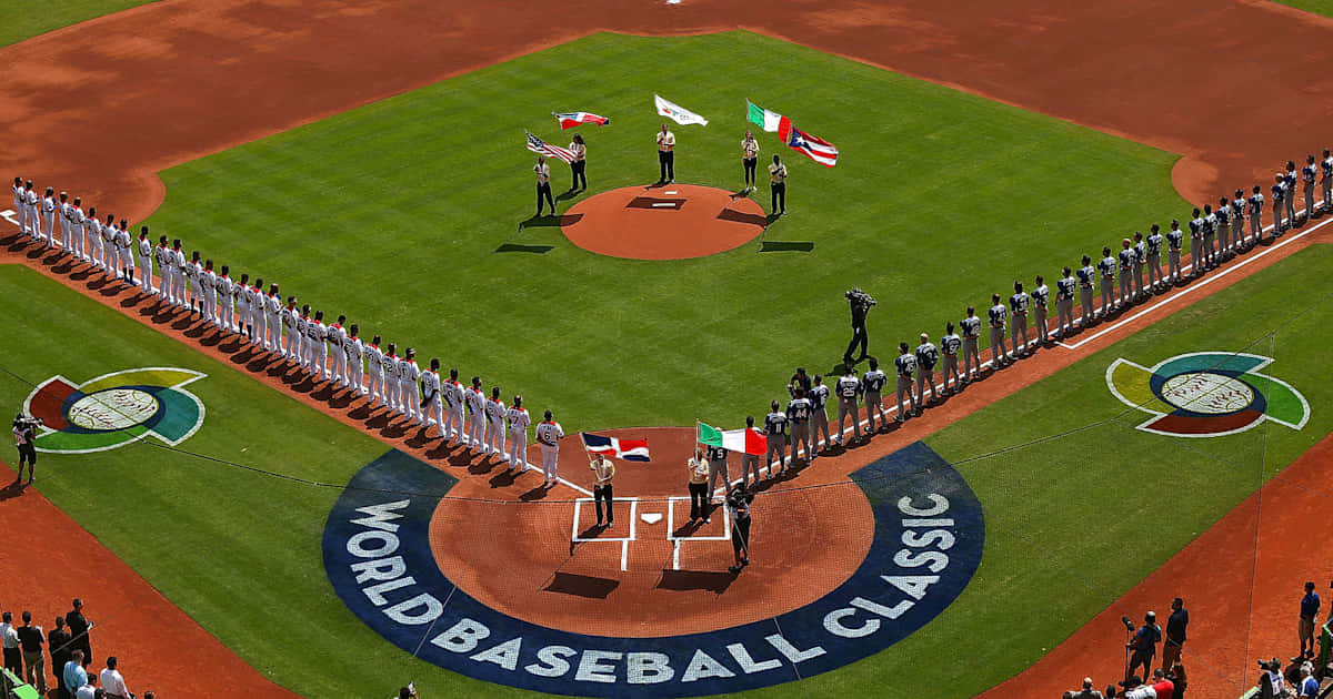 World Baseball Classic 桌布 壁紙 — 從空中俯瞰，身穿白色球衣的棒球選手在World Baseball Classic儀式中，在綠色場地上立正站好，周圍有旗幟。