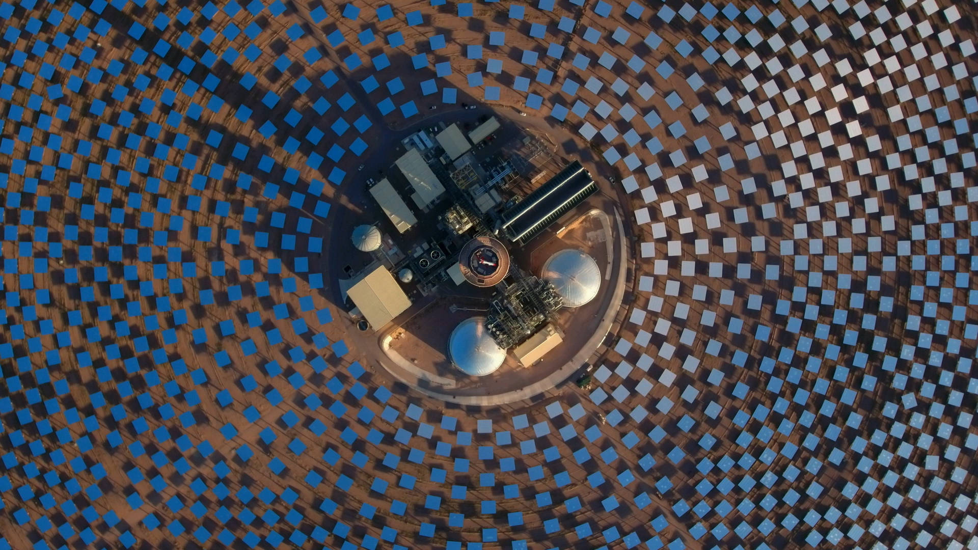 Solar Panel 桌布 壁紙 — 從空中俯瞰一座太陽能發電廠，數千塊藍色鏡子圍繞中央塔樓排列成同心圓。