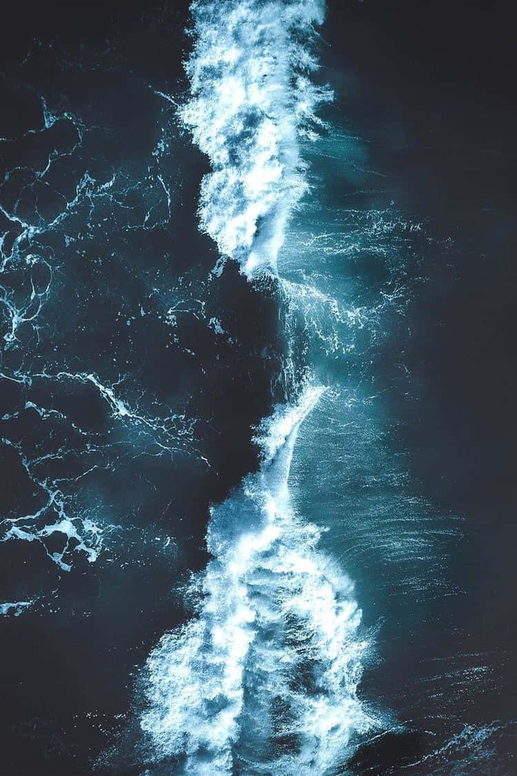 Dark Ocean 桌布 壁紙 — 從空中俯瞰一道強勁的海浪痕跡劃過深藍色海水，帶有泡沫般的白色浪花。