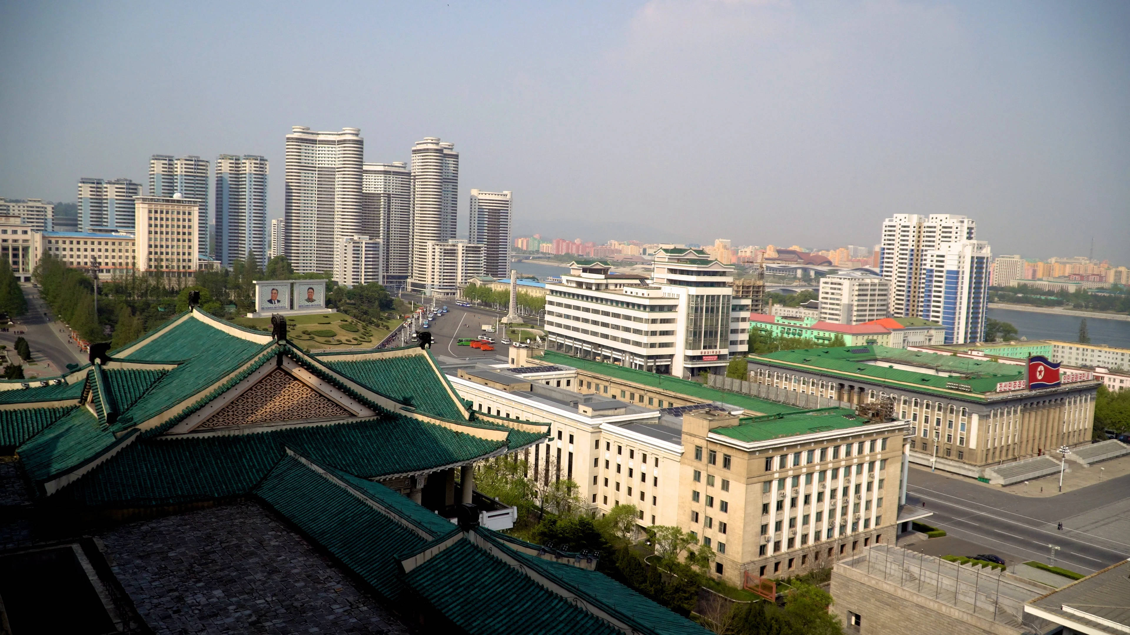 韓國 桌布 壁紙 — 從空中俯瞰城市景觀，傳統綠色屋頂建築與現代高樓大廈在朦朧天空下交融。