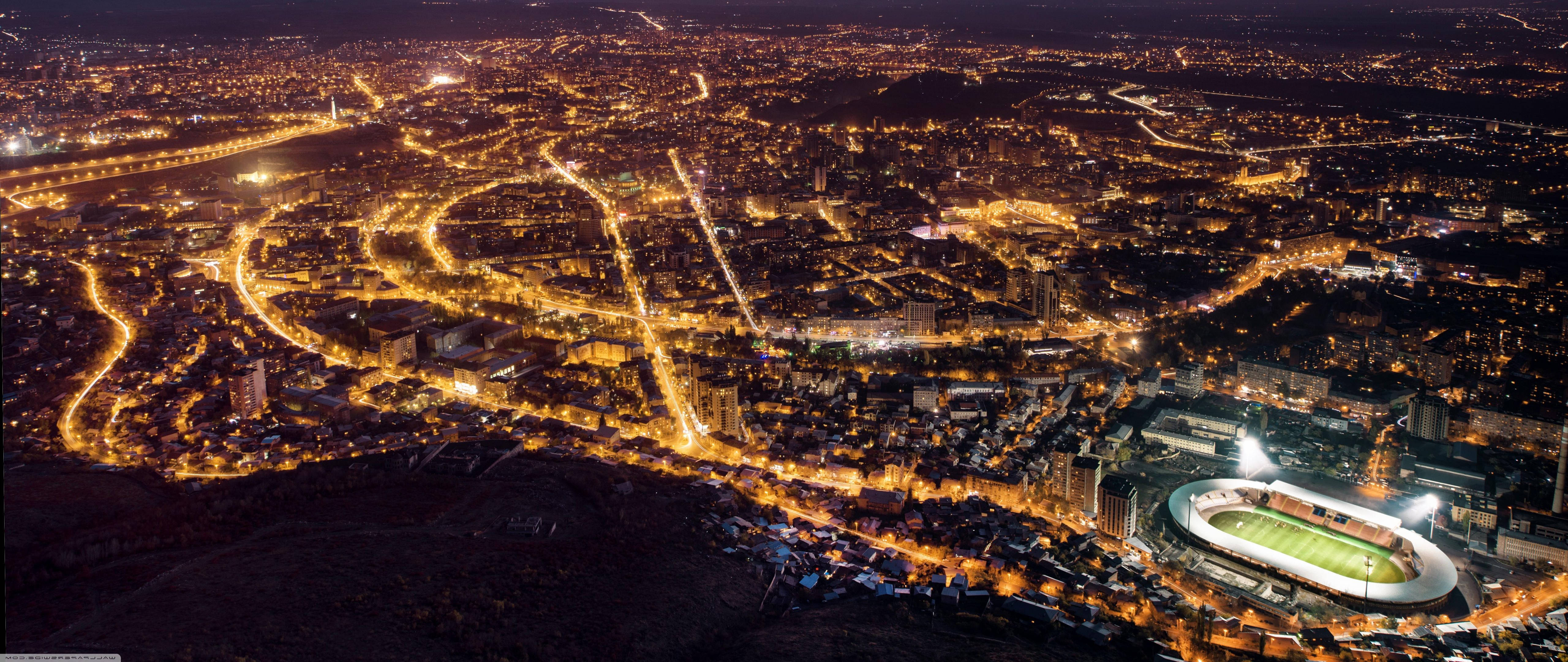 Armenia 桌布 壁紙 — 從空中俯瞰夜晚的城市，金黃色的街燈和閃爍的體育場燈光點亮了廣闊的城市景觀。