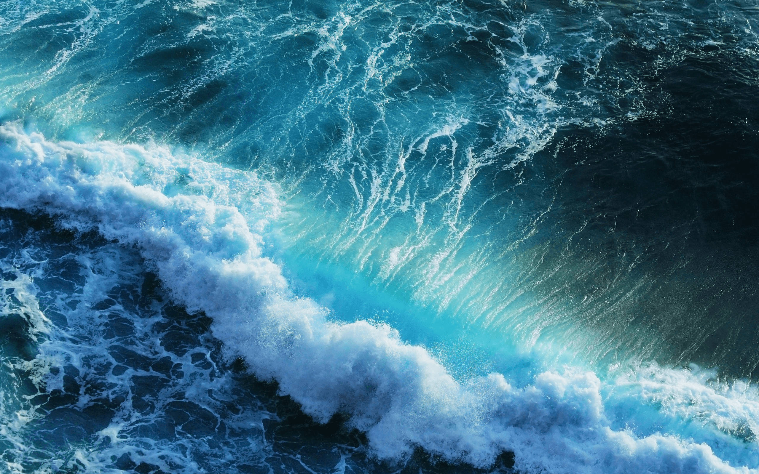 海洋 桌布 壁紙 — 從空中俯瞰強勁的海浪拍打著藍綠色和深藍色的海水，形成泡沫般的白色浪花。