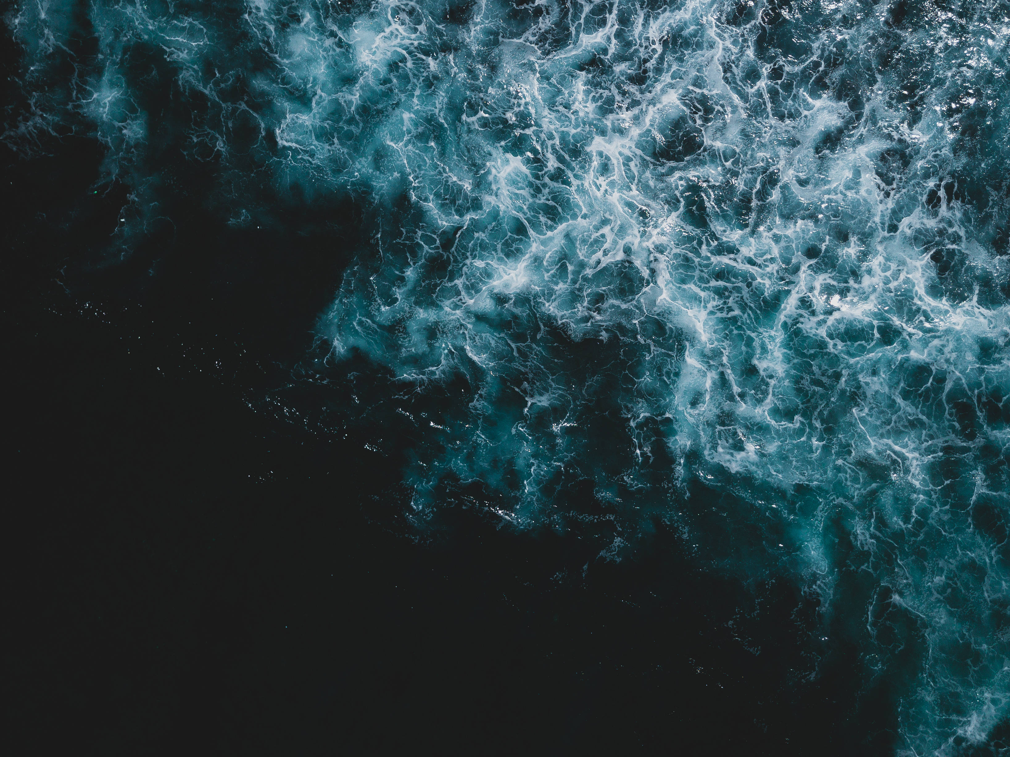 Navy 桌布 壁紙 — 從空中俯瞰洶湧的海浪拍打黑暗海水，形成複雜的白色泡沫圖案。