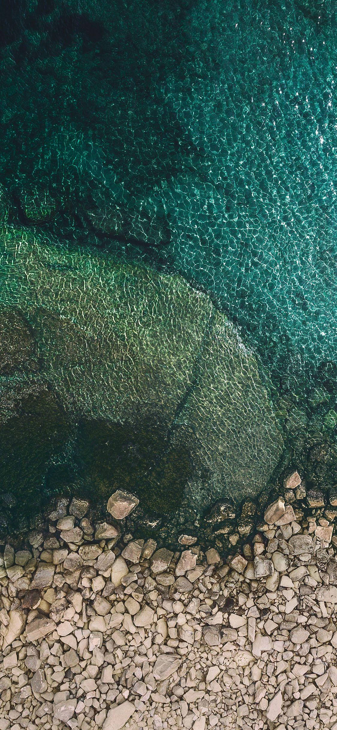 X 桌布 壁紙 — 從空中俯瞰清澈碧綠的海水，露出卵石密佈海岸線上的水下岩石。