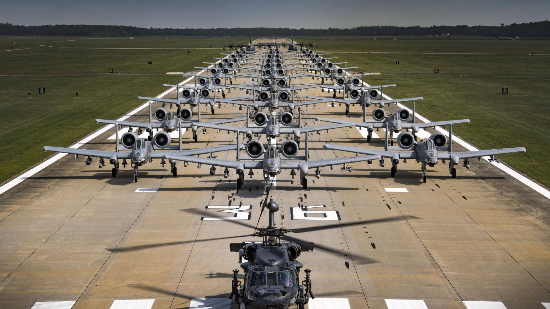 Runway 桌布 壁紙 — 從空中俯瞰眾多軍用攻擊機精確排列在停機坪上，前景有一架直升機。