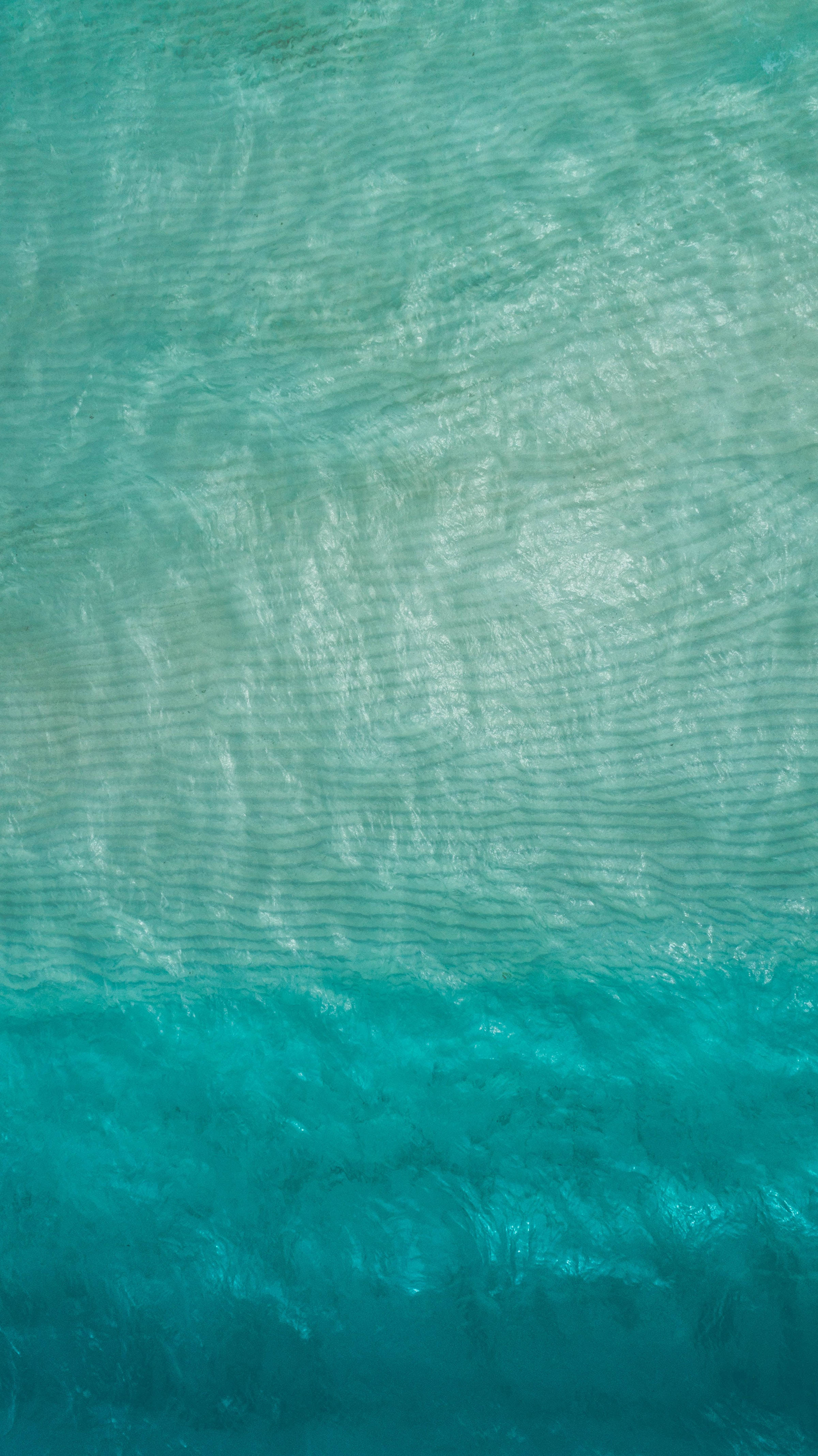 海洋藍 桌布 壁紙 — 從空中俯瞰綠松石色海浪，帶有輕柔漣漪，從淺藍到深藍的漸變。