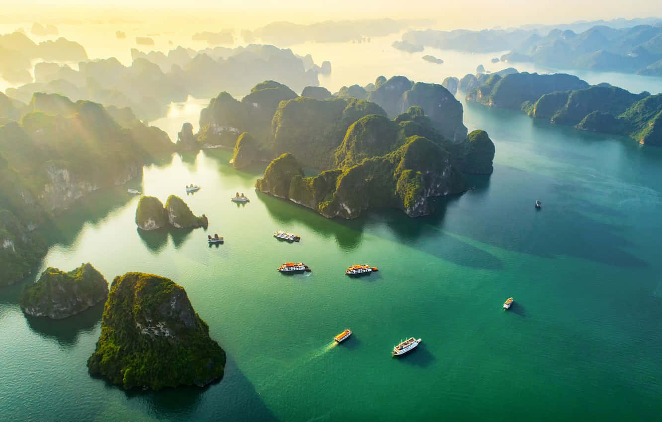 海洋 桌布 壁紙 — 從空中俯瞰翠綠海水點綴著鬱蔥的喀斯特島嶼和小船，沐浴在金色日出光芒中。