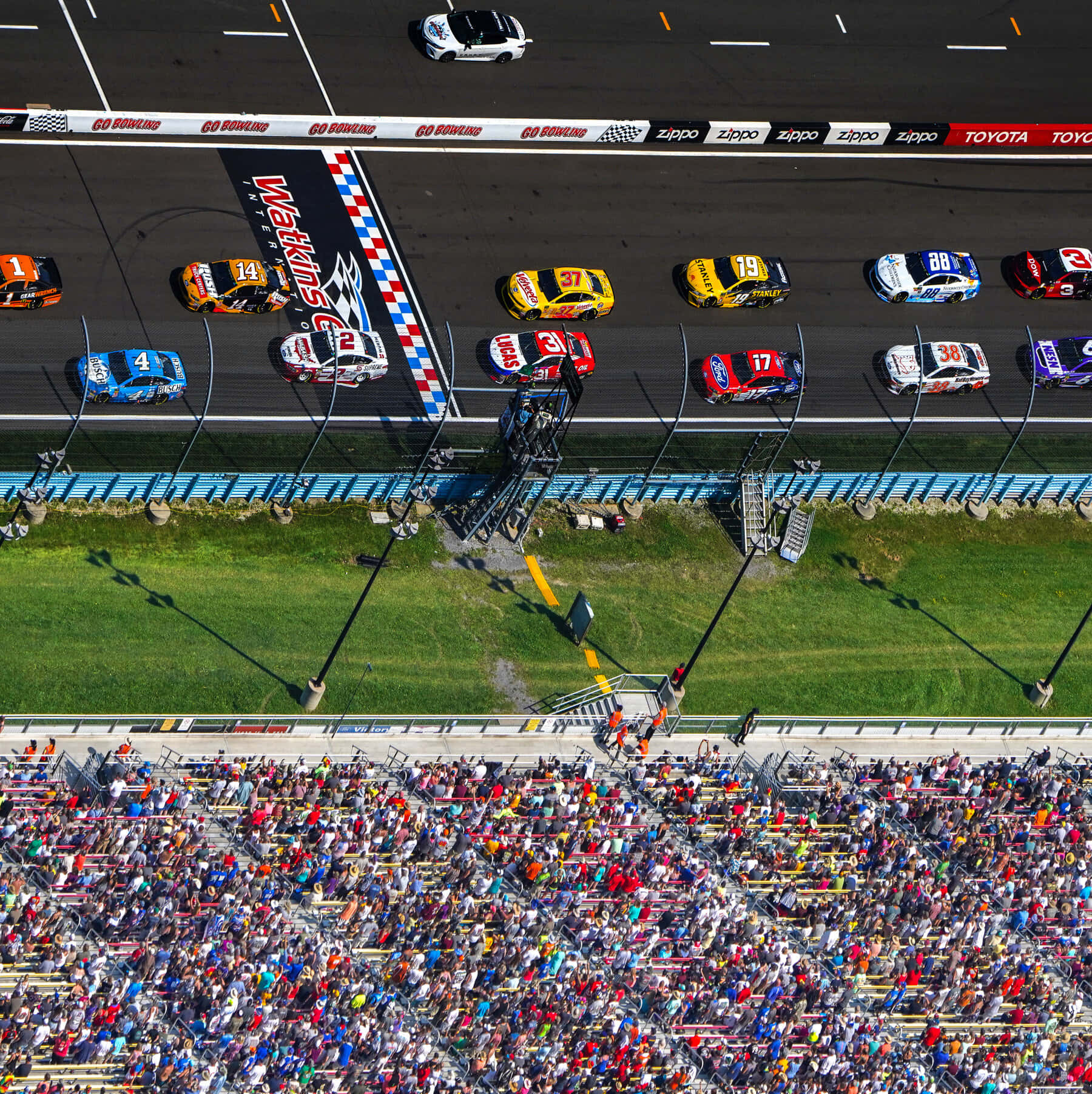 nascar 桌布 壁紙 — 從空中俯瞰馬丁斯維爾賽道，NASCAR賽車飛馳而過方格旗，下方擠滿了人群。