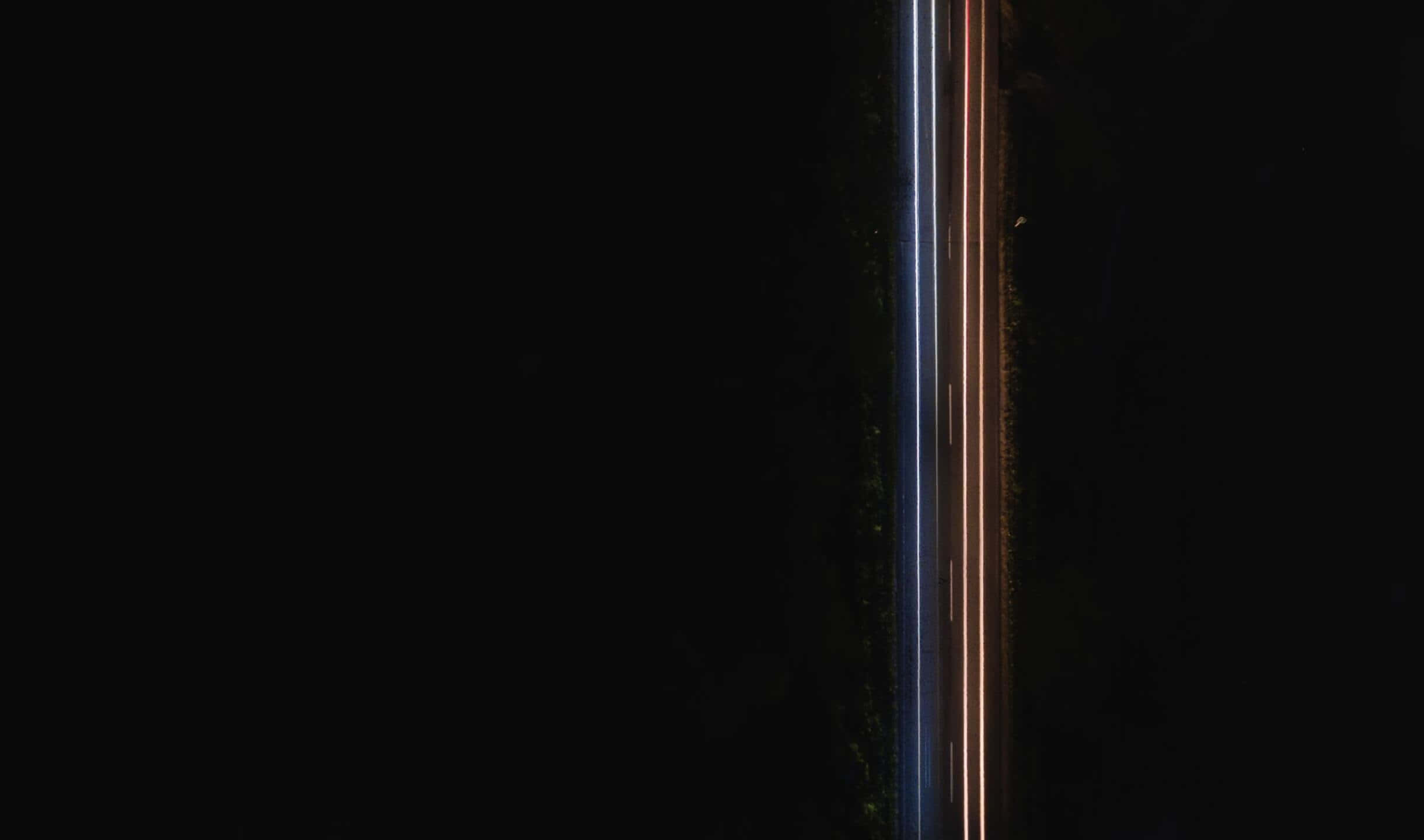 lights 桌布 壁紙 — 從空中俯瞰黑暗道路上汽車發出的發光光軌，劃破黑暗。