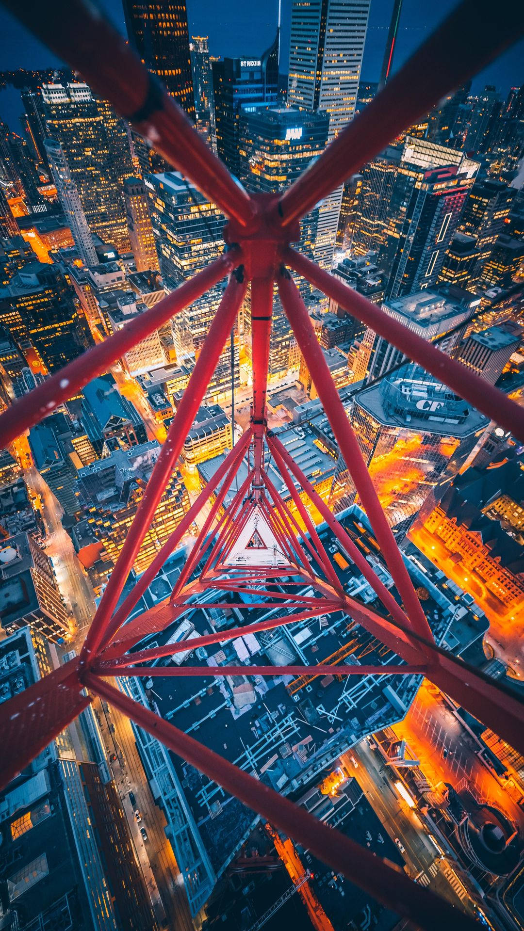 Toronto 桌布 壁紙 — 從紅色格子塔俯瞰夜晚閃爍的城市景觀，高聳的摩天大樓和街道燈火通明，呈現戲劇性的高角度視角。