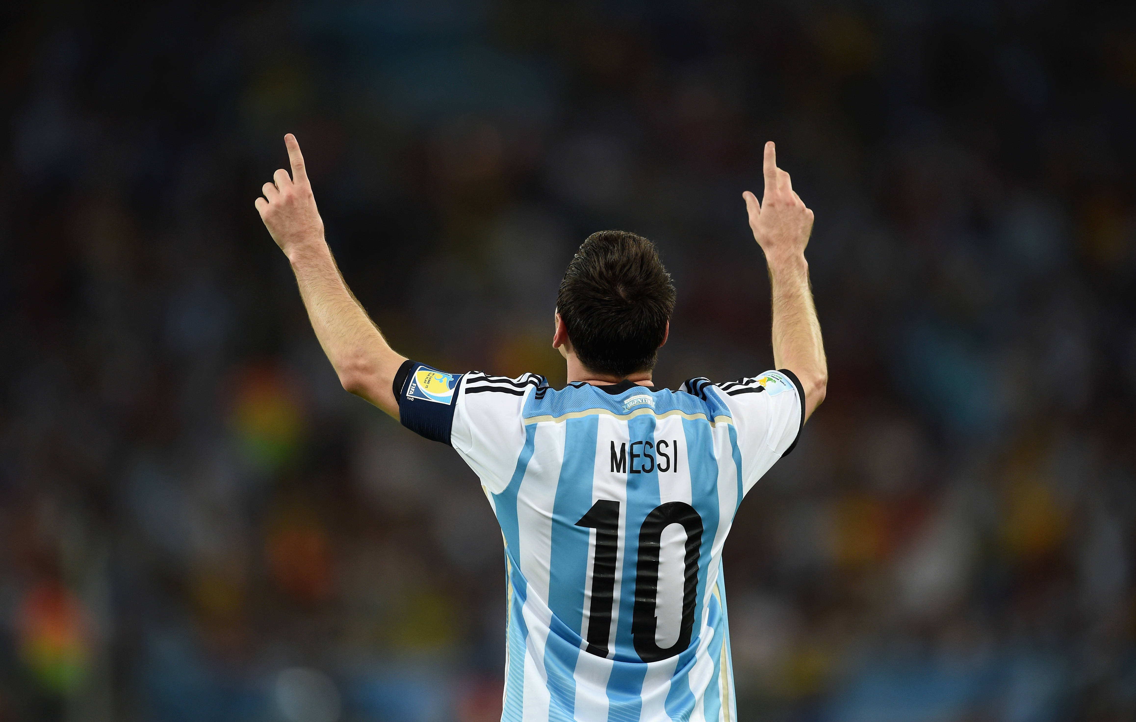 Messi 4K Ultra HD 桌布 壁紙 — 從背後看到梅西身穿阿根廷球衣在球場上舉起雙食指做出勝利手勢。