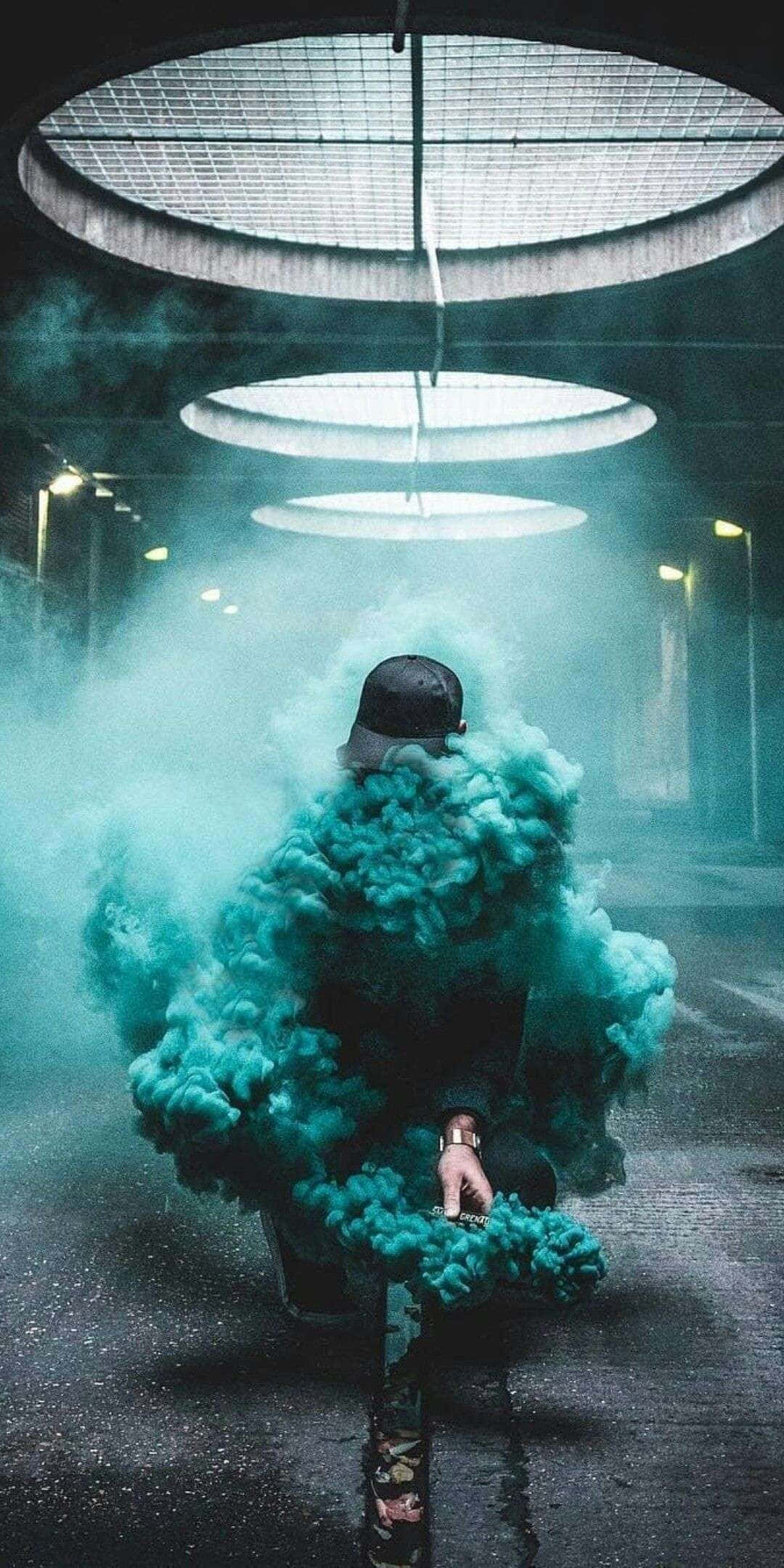 Smoke Blue 桌布 壁紙 — 從背後看到的一個人，在昏暗的城市隧道中，圓形天窗下被旋轉的藍綠色煙霧籠罩。