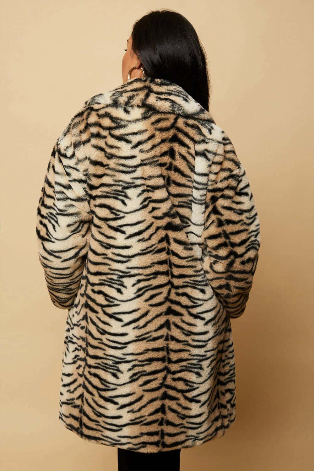Animal Fur 桌布 壁紙 — 從背後看到的一個人穿著毛絨老虎條紋人造毛皮大衣，背景為純米色。