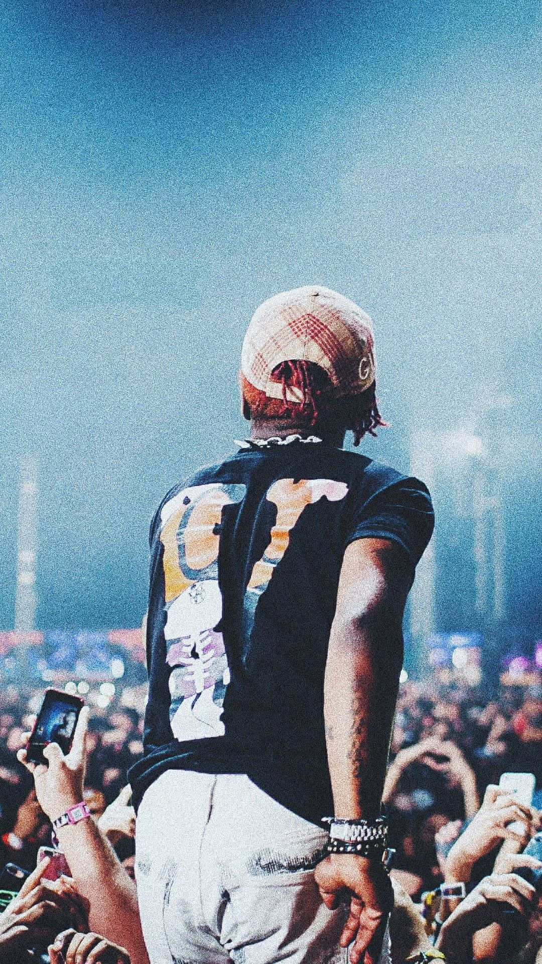 Lil Uzi Album 桌布 壁紙 — 從背後看到的表演者，身處音樂會舞台上，人群在藍色煙霧燈光下高舉手機。