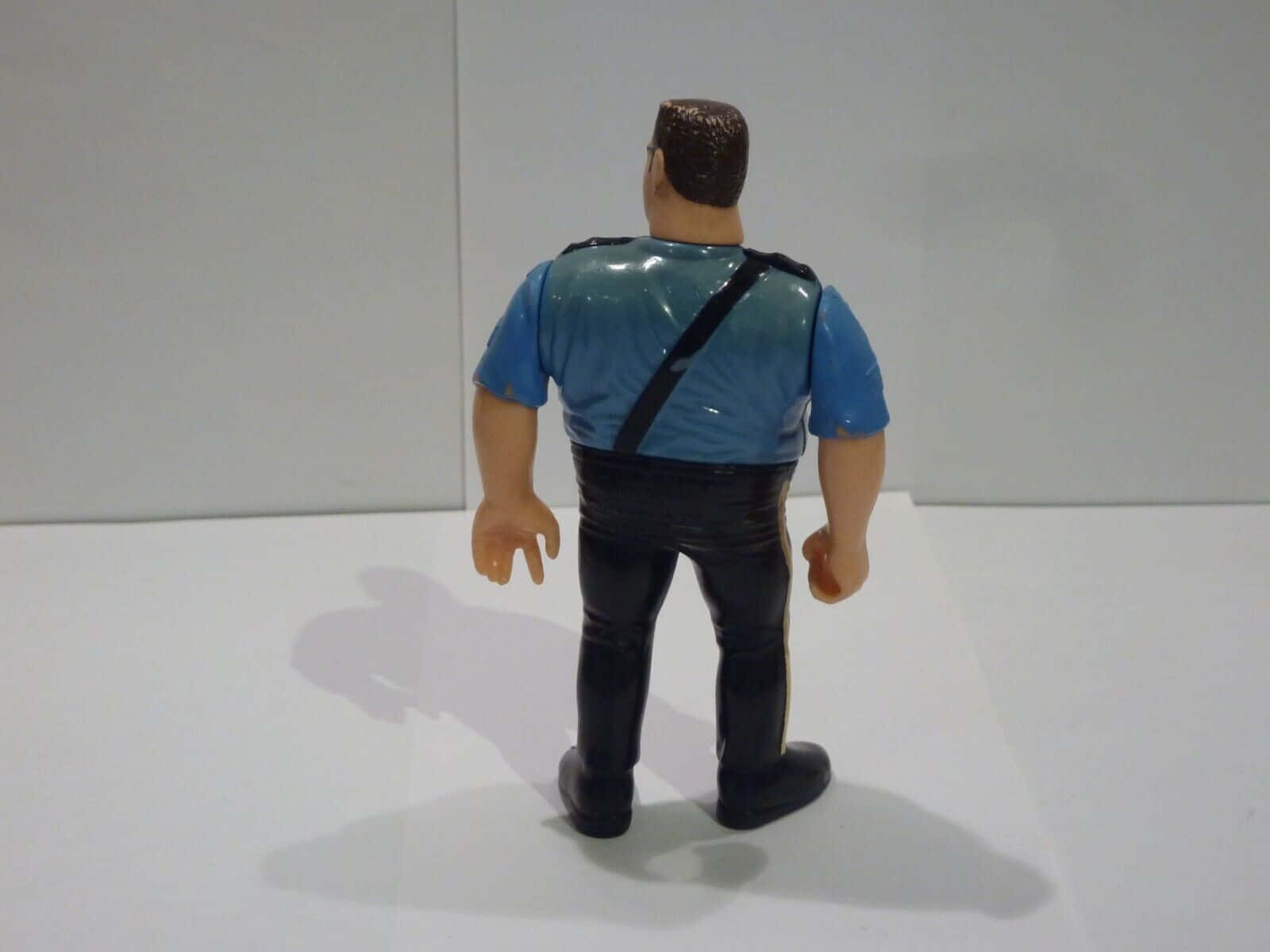 Big Boss Man 桌布 壁紙 — 從背後觀看一個站立在白色表面上的警察塑膠動作公仔。