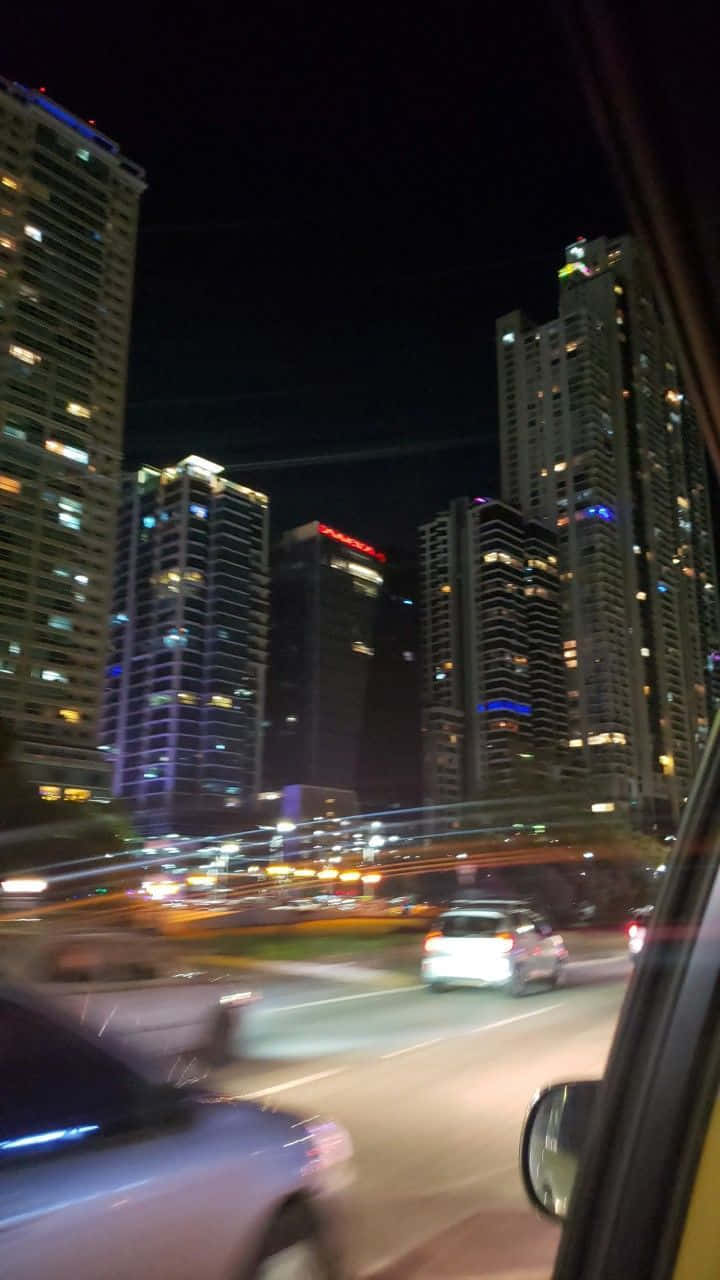 Blur 桌布 壁紙 — 從行駛中的汽車觀看的夜景城市景觀，模糊的光線掠過高聳的照明摩天大樓。
